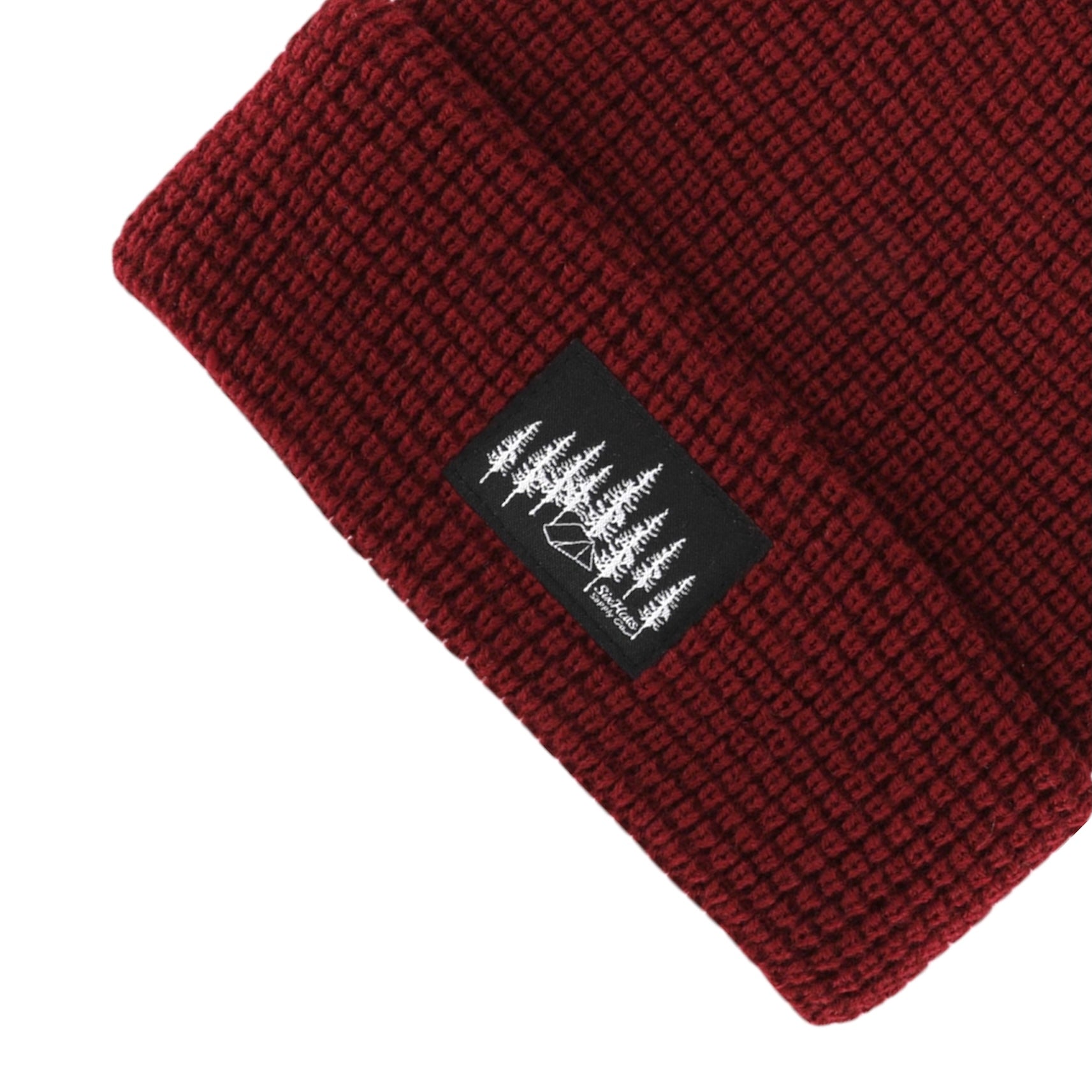 Burgundy Explorer Waffle Beanie displayed on a wooden surface, showcasing its thick knitted texture and stylish design.