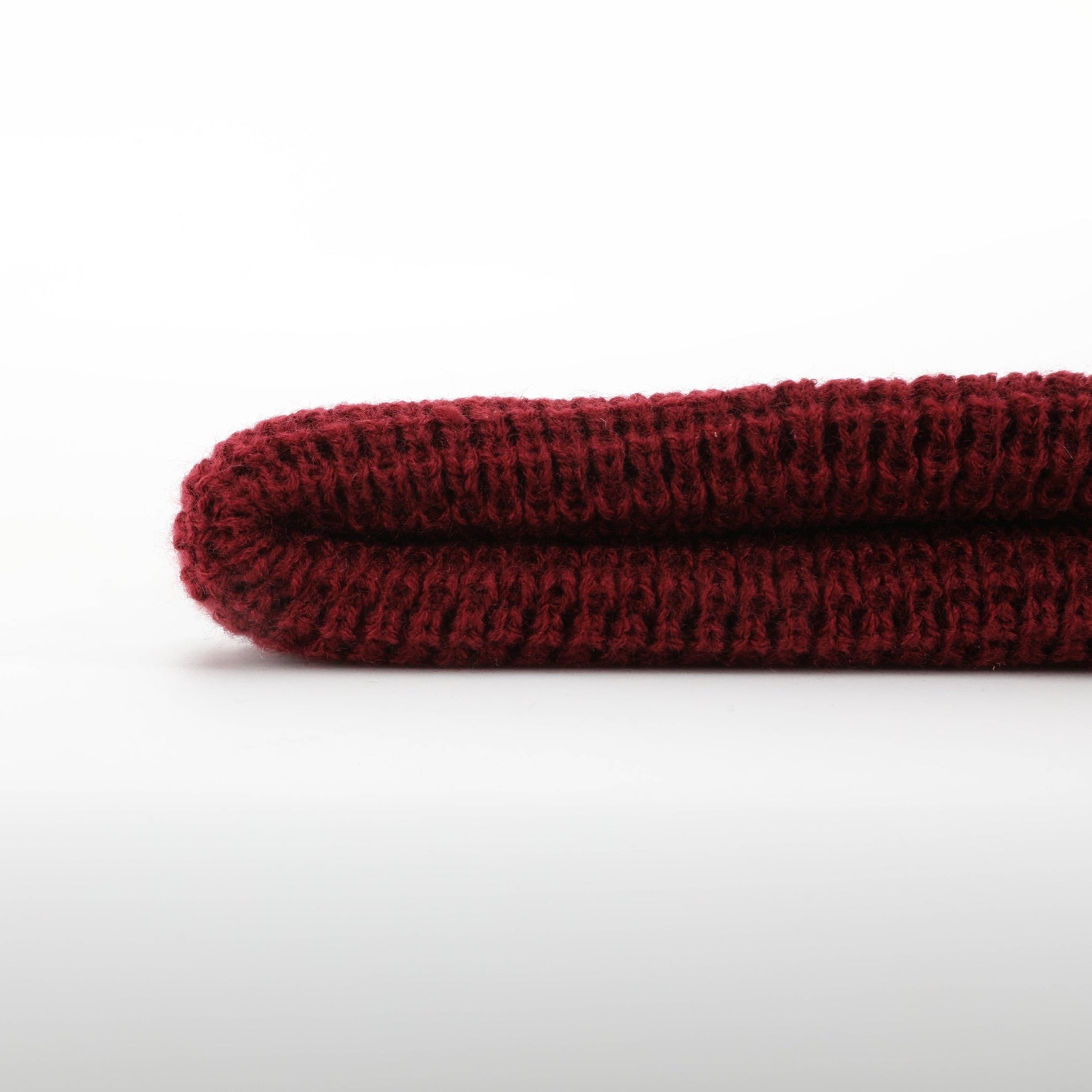 Burgundy Explorer Waffle Beanie displayed on a wooden surface, showcasing its thick knitted texture and stylish design.