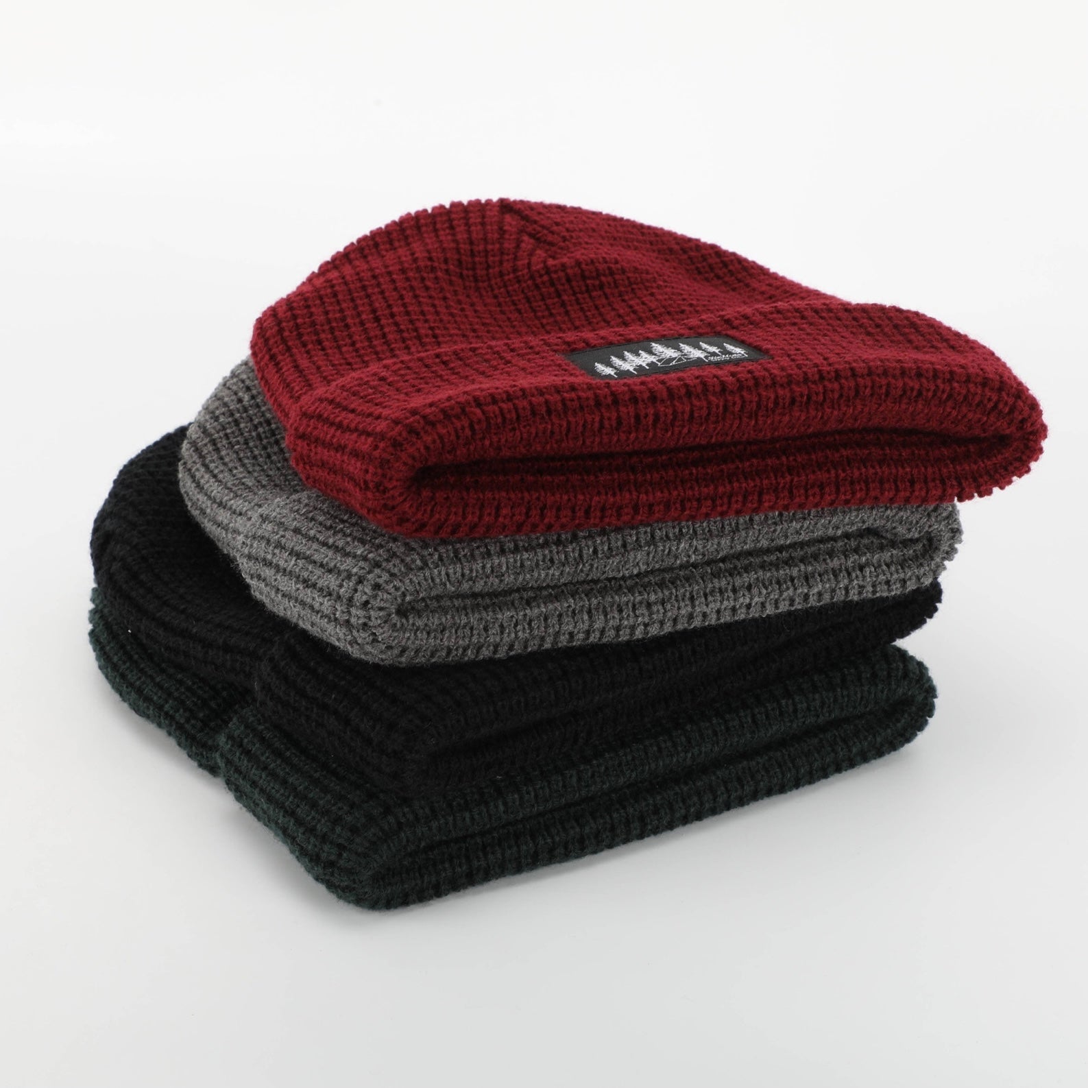 Burgundy Explorer Waffle Beanie displayed on a wooden surface, showcasing its thick knitted texture and stylish design.