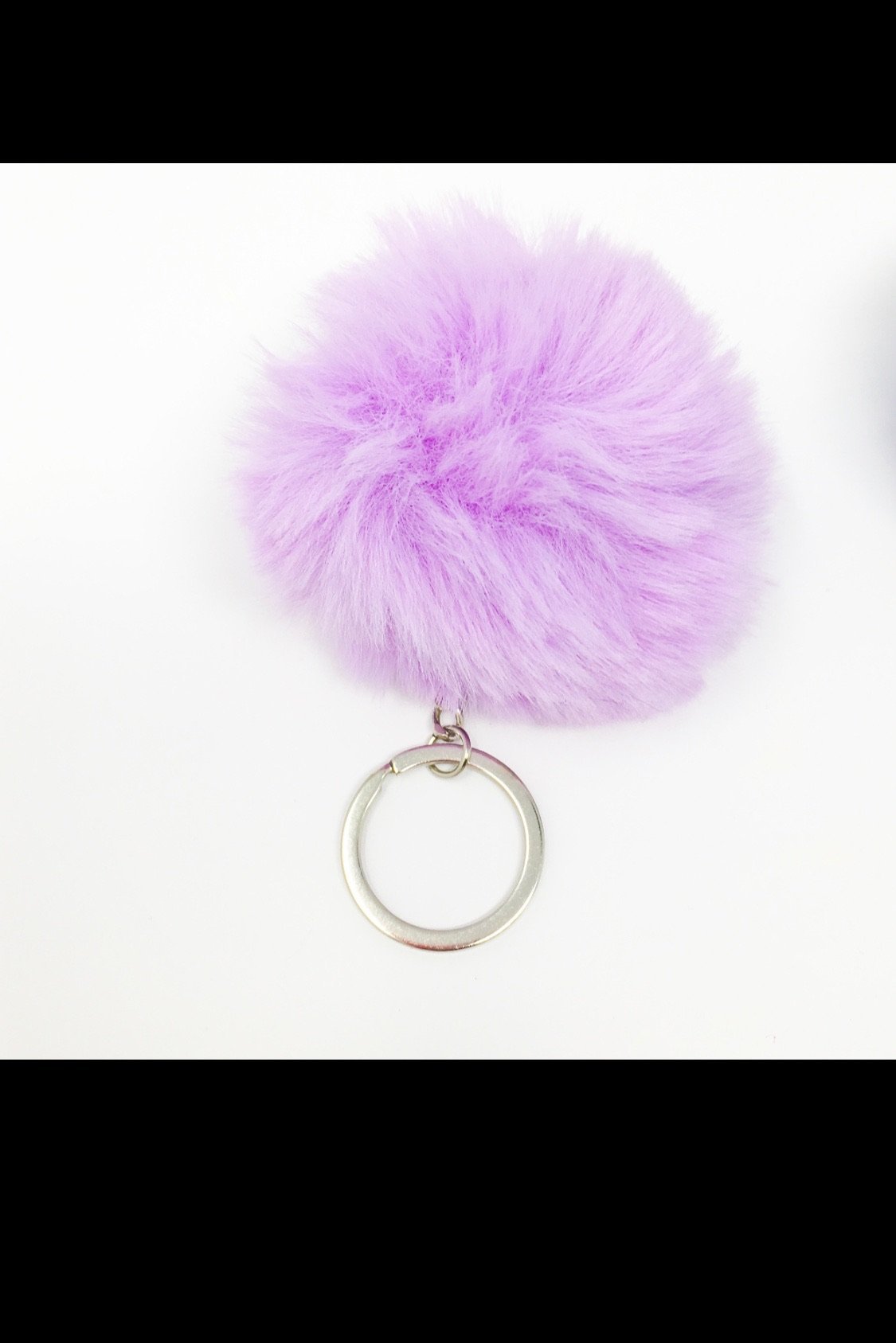 A colorful assortment of Puffs Keychains featuring fuzzy ball designs in purple, pink, white, black, red, and blue, showcasing their vibrant colors and textures.