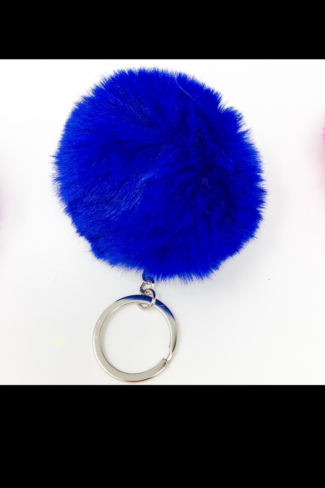 A colorful assortment of Puffs Keychains featuring fuzzy ball designs in purple, pink, white, black, red, and blue, showcasing their vibrant colors and textures.