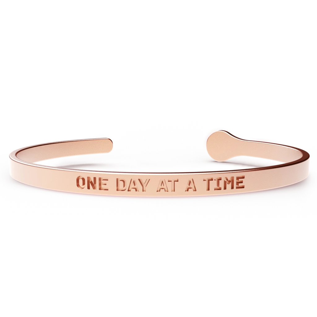 A stylish ONE DAY AT A TIME bracelet made of hypoallergenic stainless steel with a 24k gold coating, designed to fit most wrist sizes.