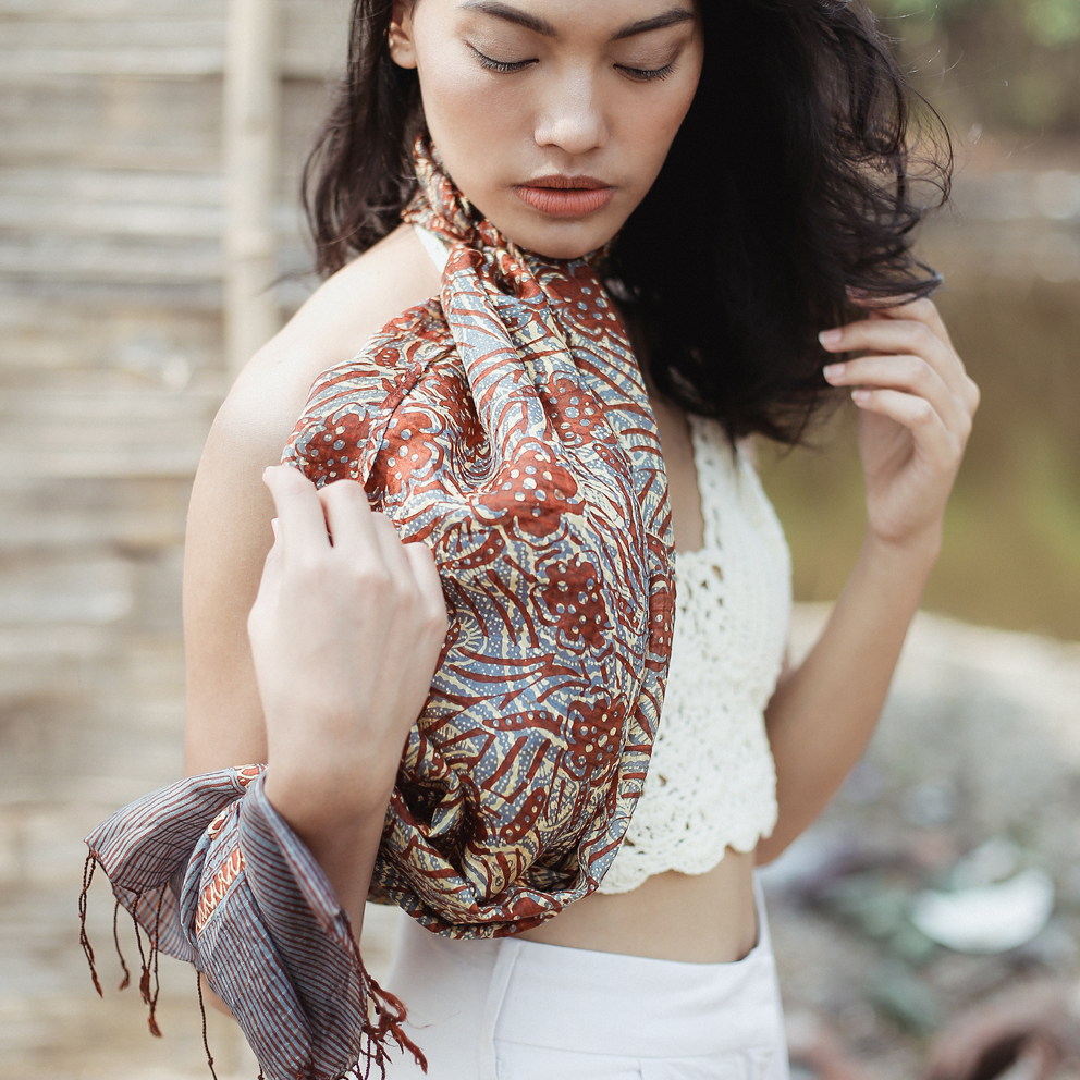 Cempaka Silk Batik Scarf featuring intricate floral patterns, hand-stamped in vibrant colors, elegantly draped on a neutral background.