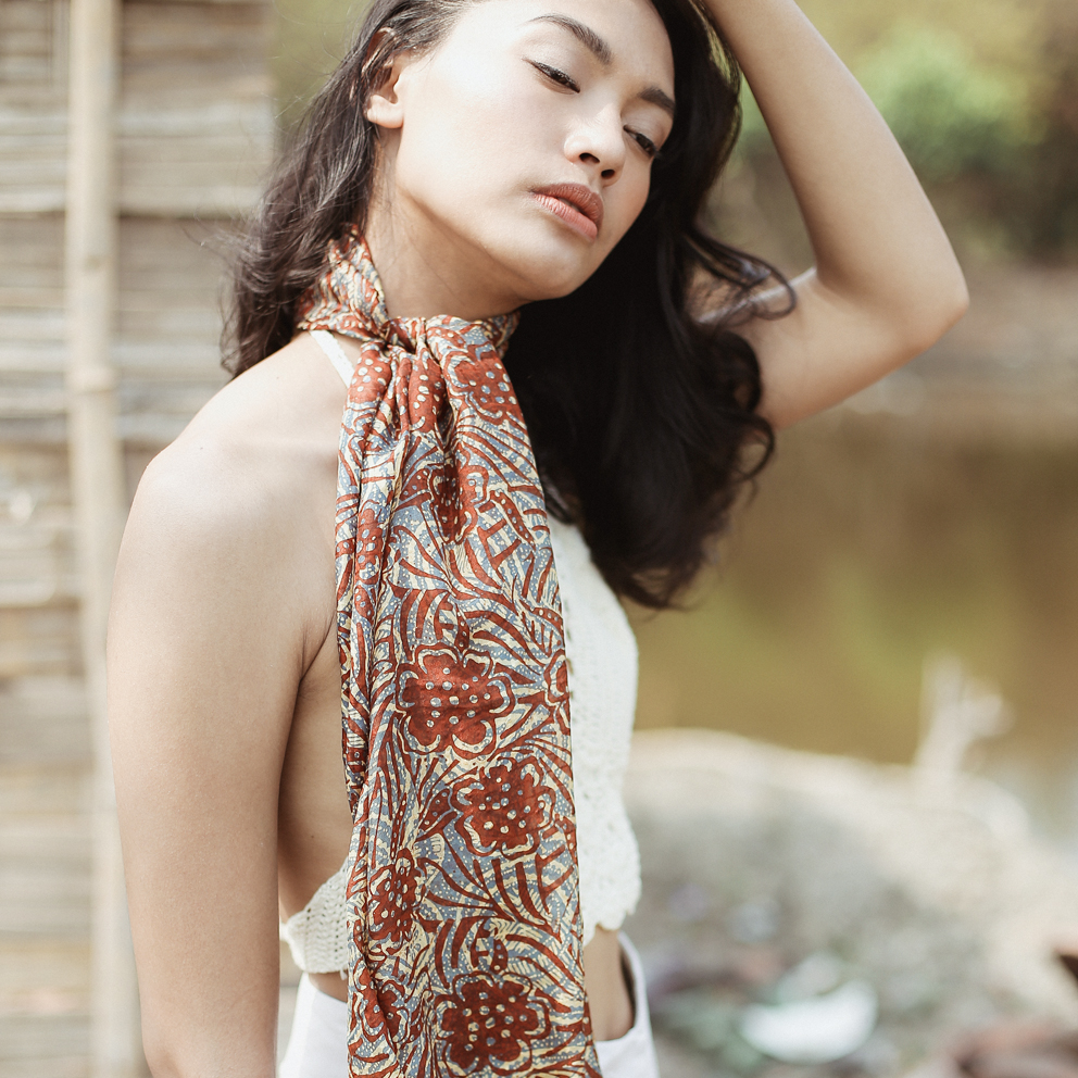 Cempaka Silk Batik Scarf featuring intricate floral patterns, hand-stamped in vibrant colors, elegantly draped on a neutral background.