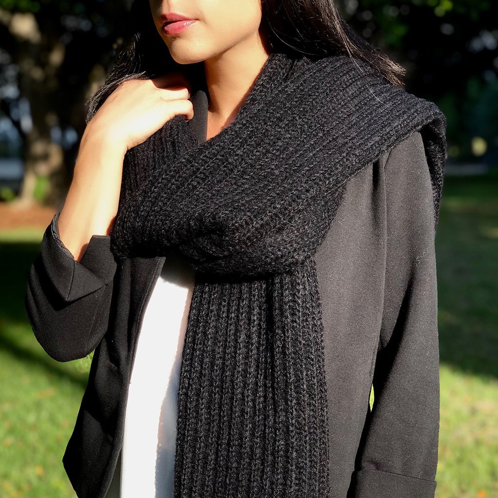 Chunky black knit alpaca scarf, oversized and unisex, showcasing its luxurious texture and unique handmade quality.