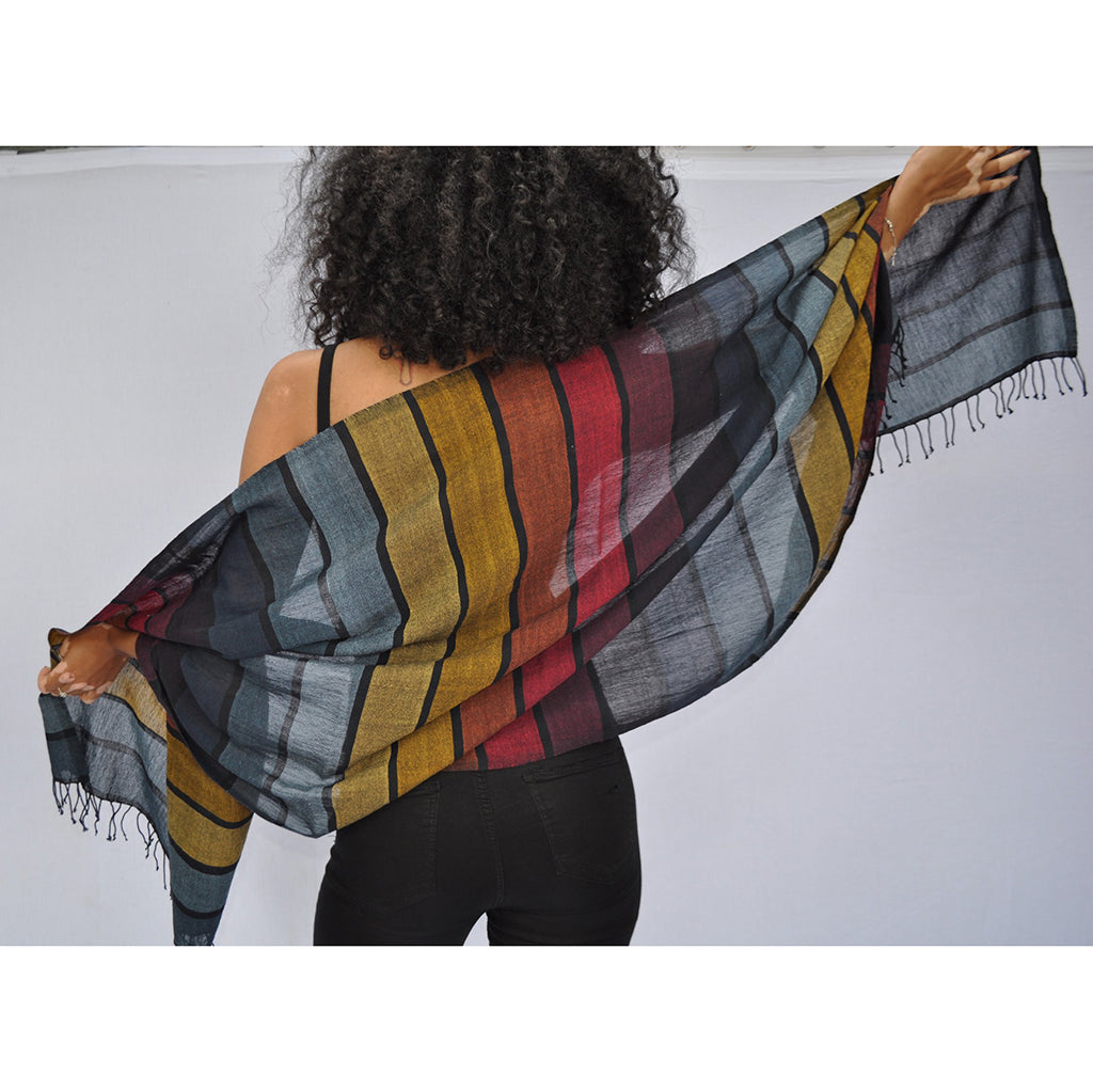 A vibrant Rainbow Wrap Scarf made from pure Ethiopian cotton with black fringe edges, showcasing its unique design and craftsmanship.