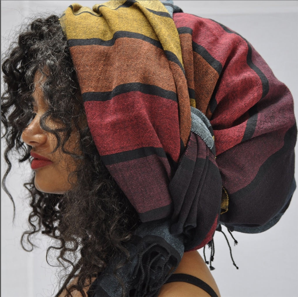 A vibrant Rainbow Wrap Scarf made from pure Ethiopian cotton with black fringe edges, showcasing its unique design and craftsmanship.