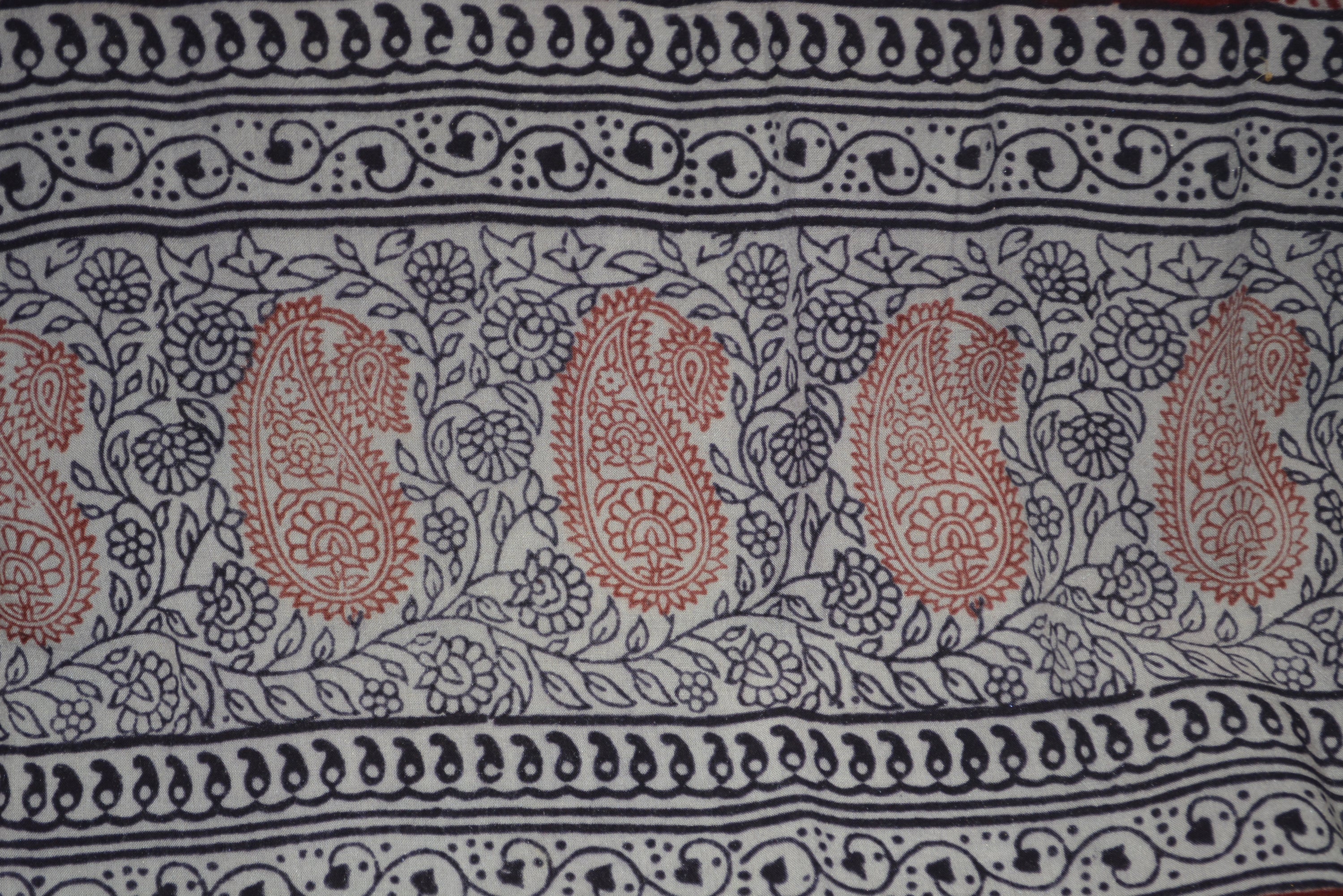 Red and black paisley design hand block printed cotton fabric showcasing intricate floral patterns and vintage motifs.