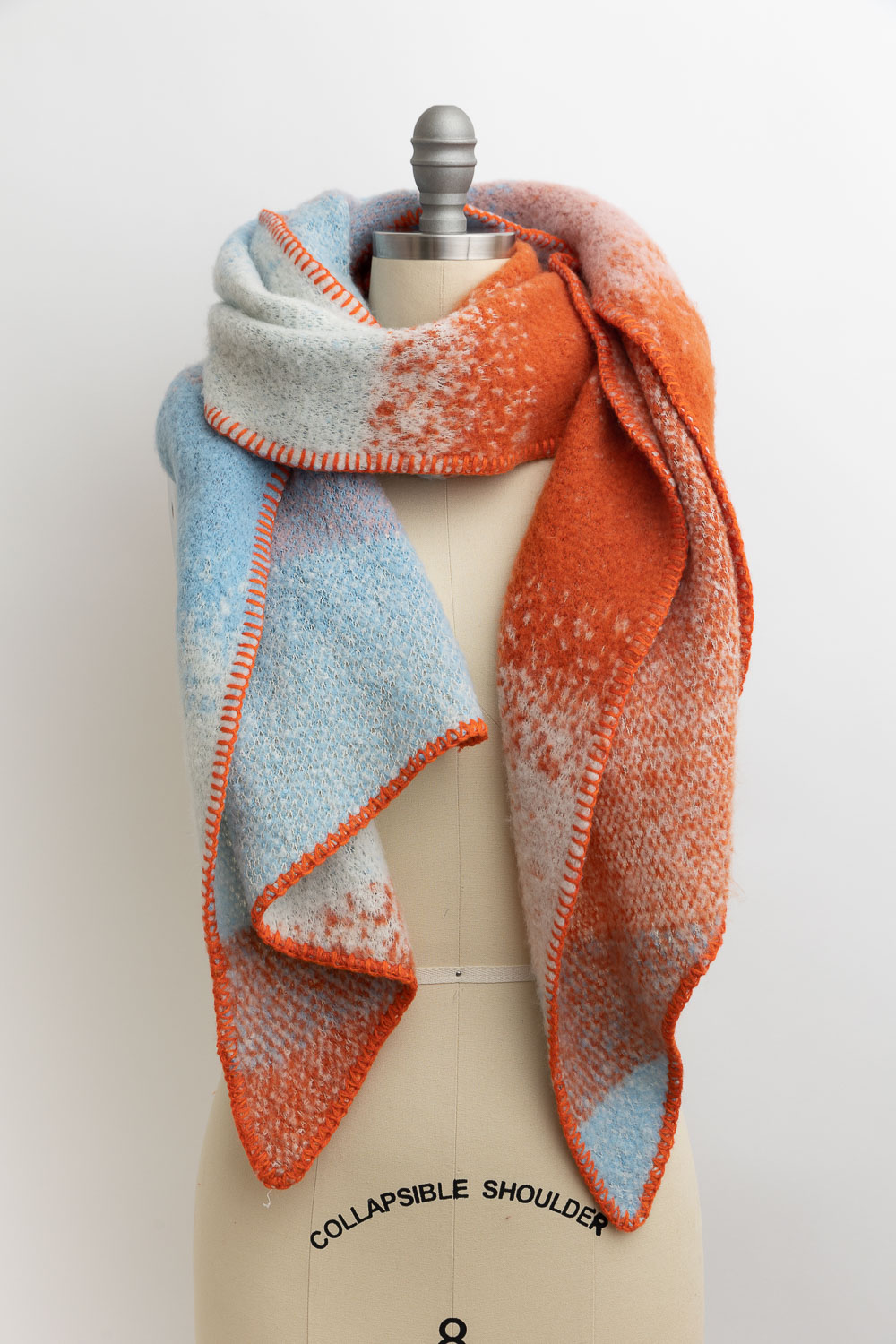 A vibrant ultra soft multi colored scarf draped elegantly, showcasing its warm hues and soft texture.