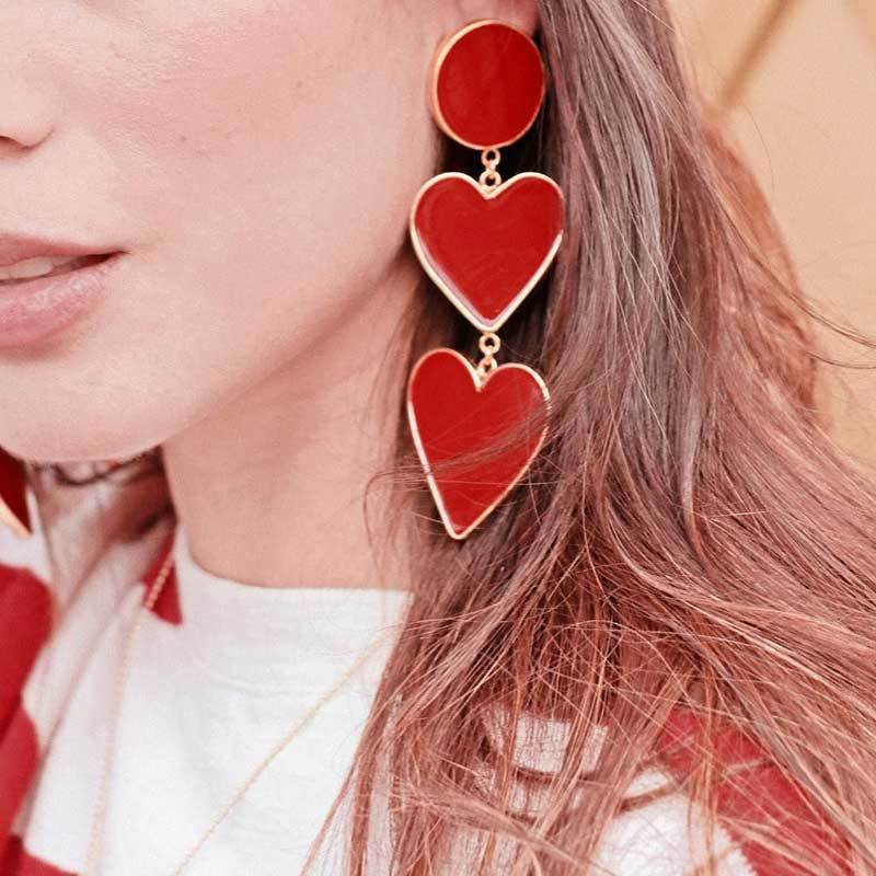 A pair of elegant red heart earrings with gold plating, featuring a double heart drop design and post back closure.
