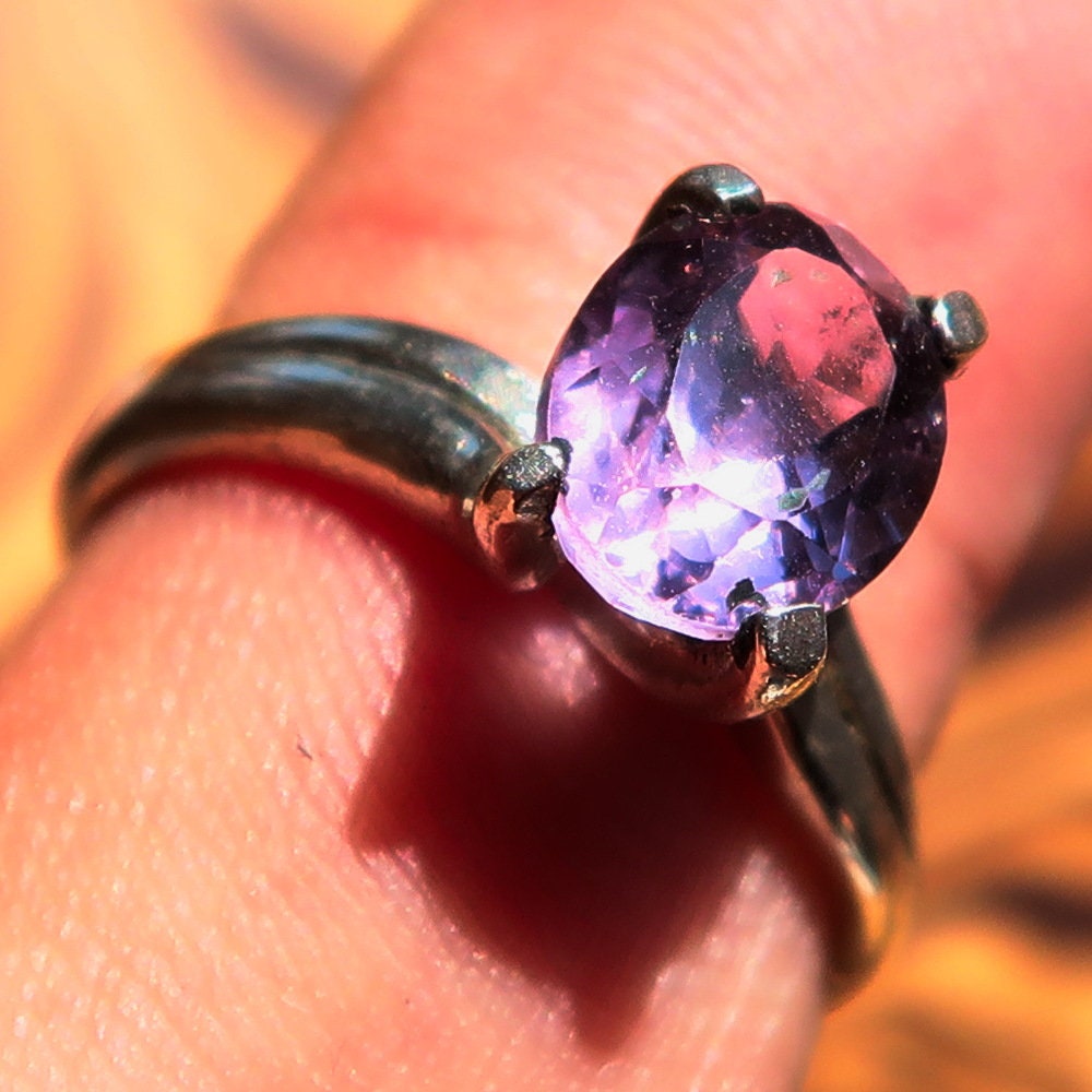 A stunning sterling silver solitaire ring featuring a vibrant oval-shaped purple amethyst, showcasing elegance and craftsmanship.