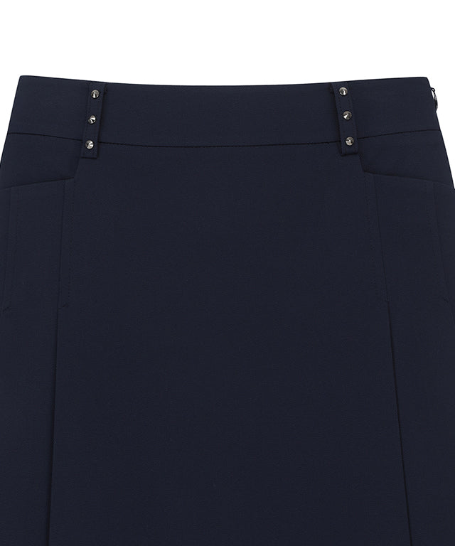 Navy A-line skirt with two-tier pleats, featuring a D-ring logo and color point tape at the hem.