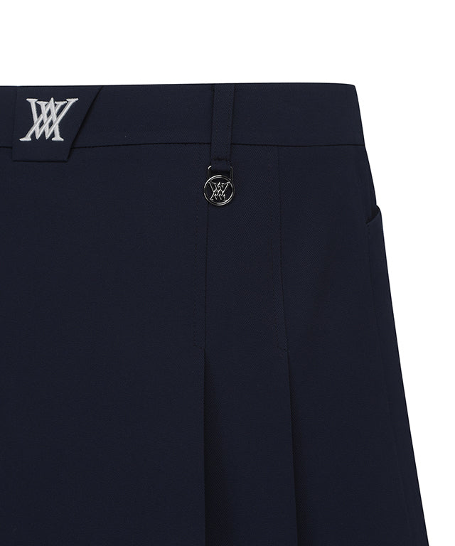 Navy A-line skirt with two-tier pleats, featuring a D-ring logo and color point tape at the hem.