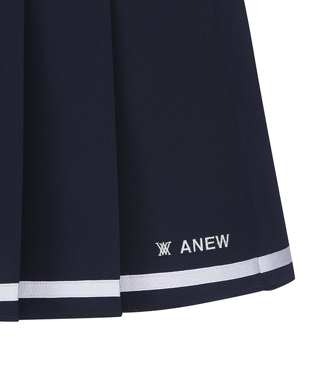 Navy A-line skirt with two-tier pleats, featuring a D-ring logo and color point tape at the hem.