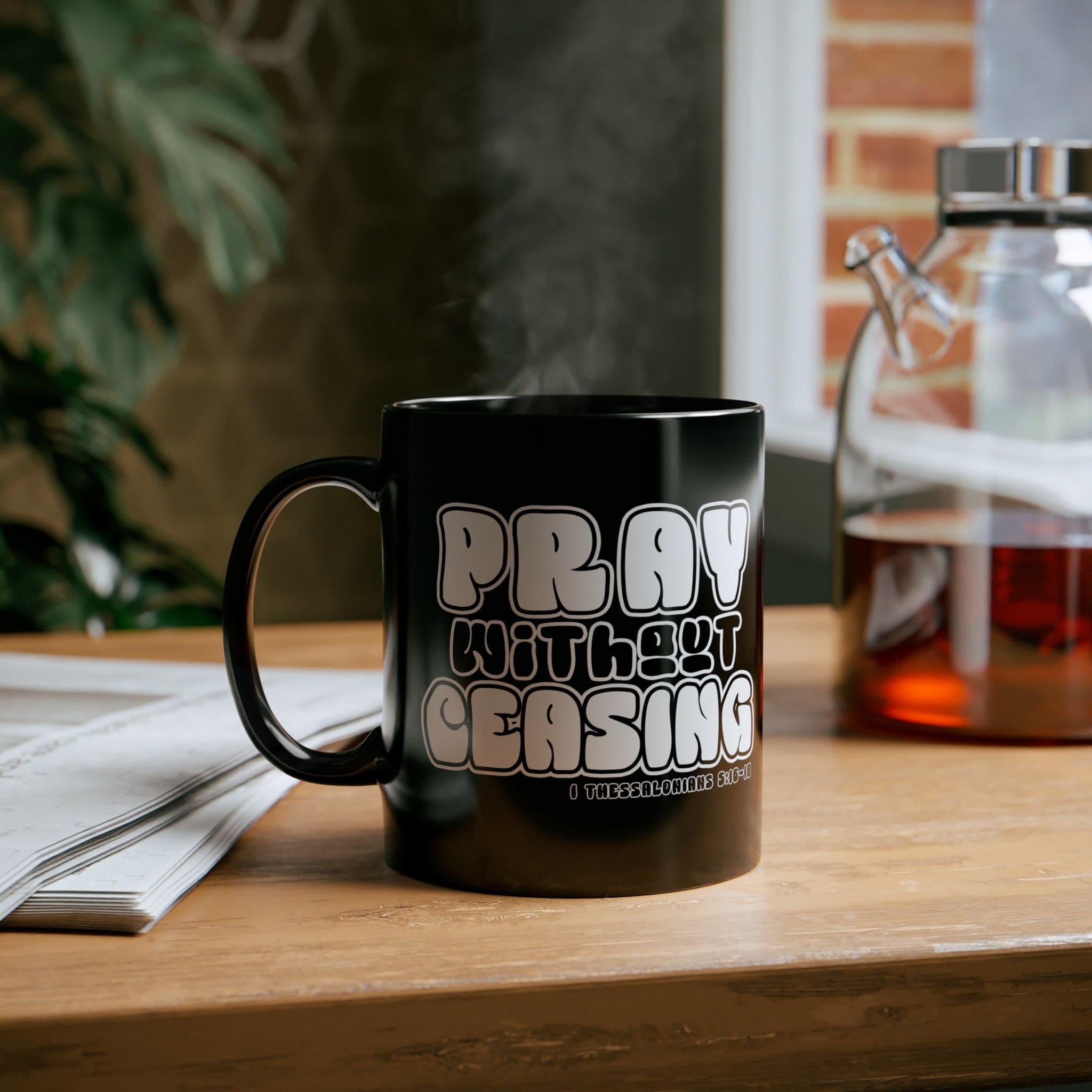 Black ceramic mug with 'Pray Without Ceasing' inspirational design, perfect for coffee or tea.