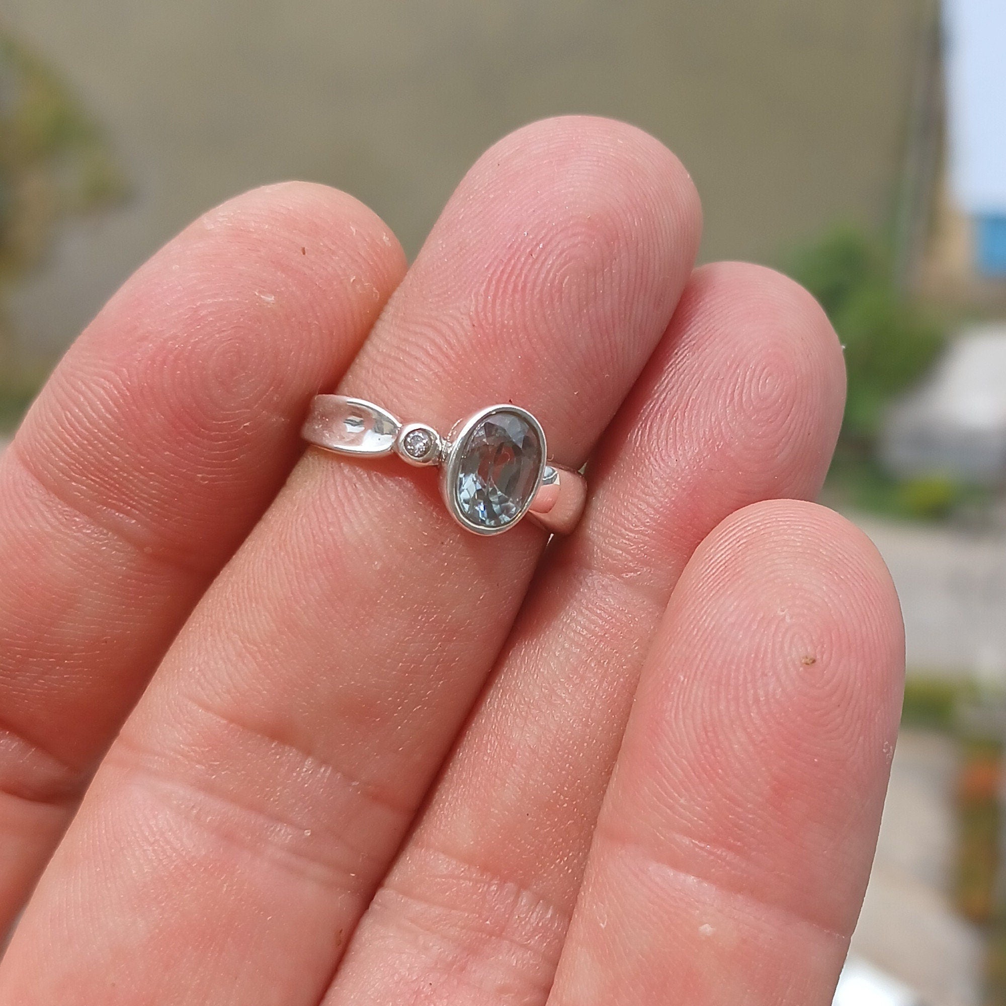 A beautiful Blue Aquamarine Ring set in polished sterling silver, featuring a minimalist solitaire design with an oval cut gemstone and CZ accents.