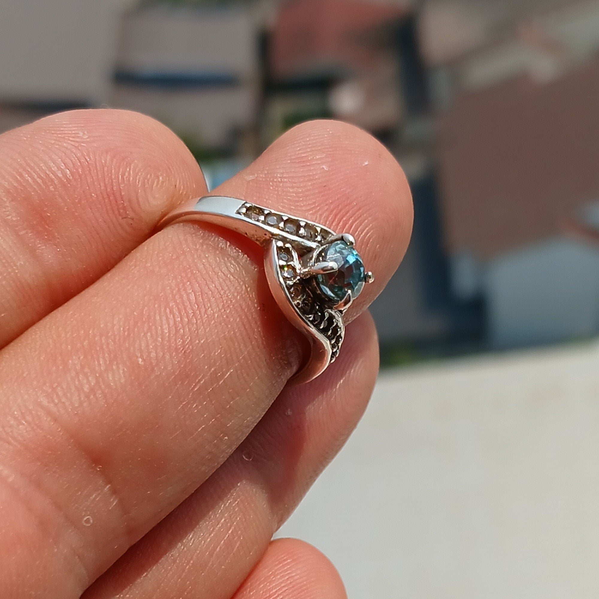 Handmade sterling silver ring featuring a round cut Blue Zircon gemstone surrounded by 18 cubic zirconia stones, showcasing elegance and sophistication.