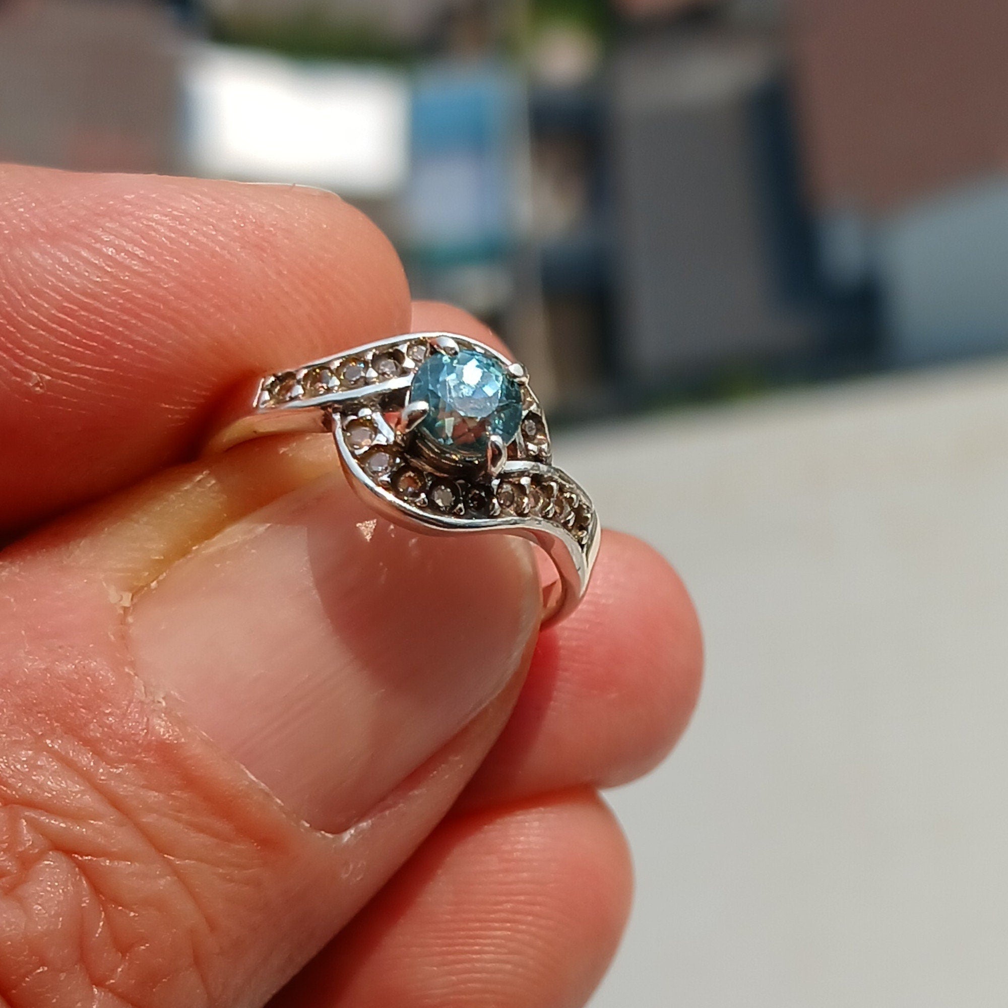 Handmade sterling silver ring featuring a round cut Blue Zircon gemstone surrounded by 18 cubic zirconia stones, showcasing elegance and sophistication.