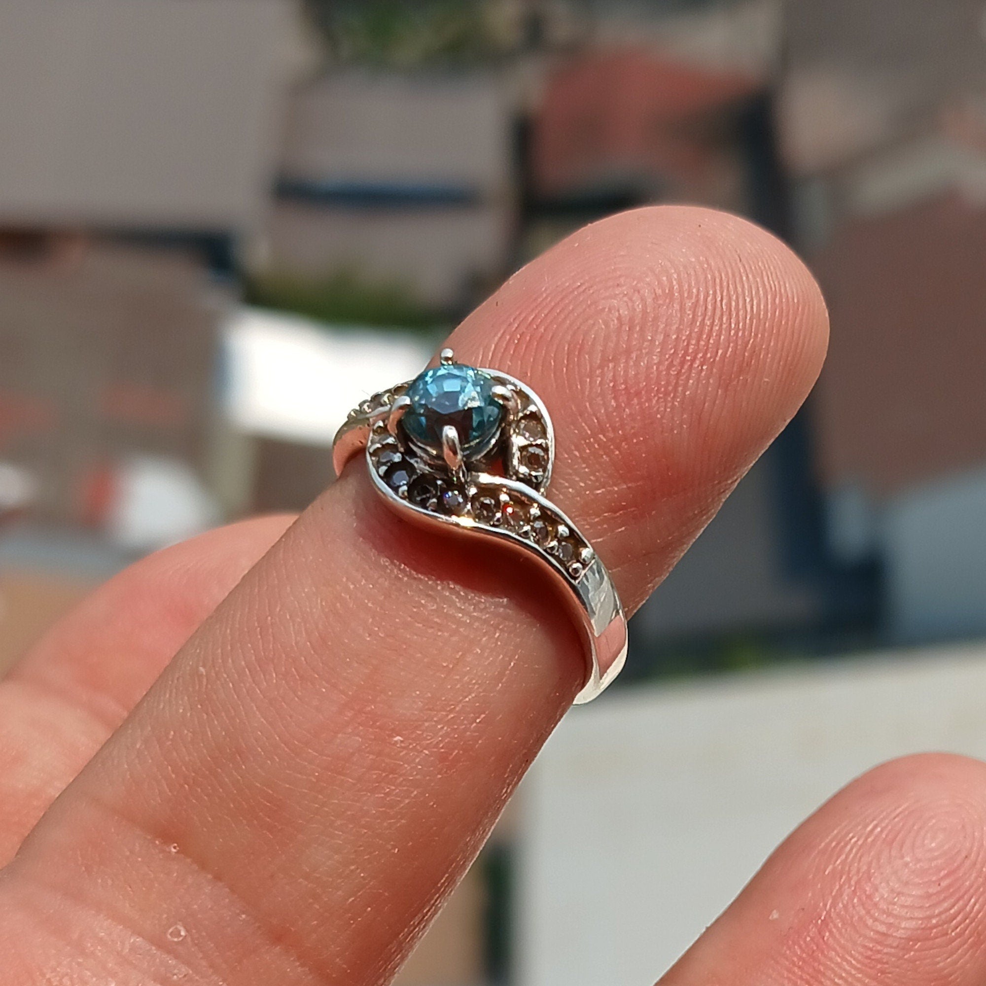 Handmade sterling silver ring featuring a round cut Blue Zircon gemstone surrounded by 18 cubic zirconia stones, showcasing elegance and sophistication.