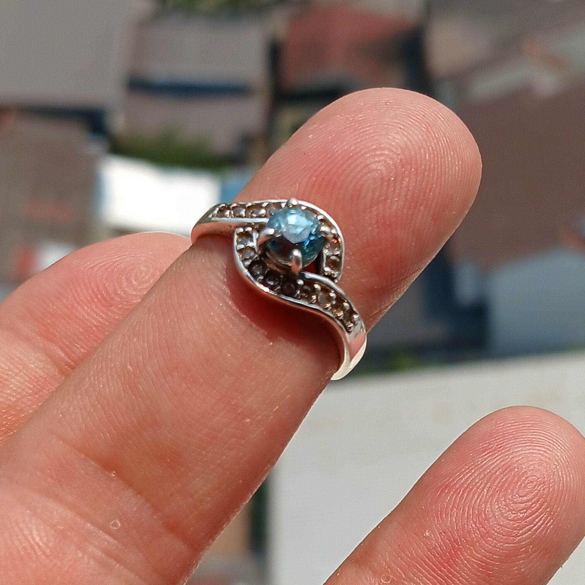 Handmade sterling silver ring featuring a round cut Blue Zircon gemstone surrounded by 18 cubic zirconia stones, showcasing elegance and sophistication.