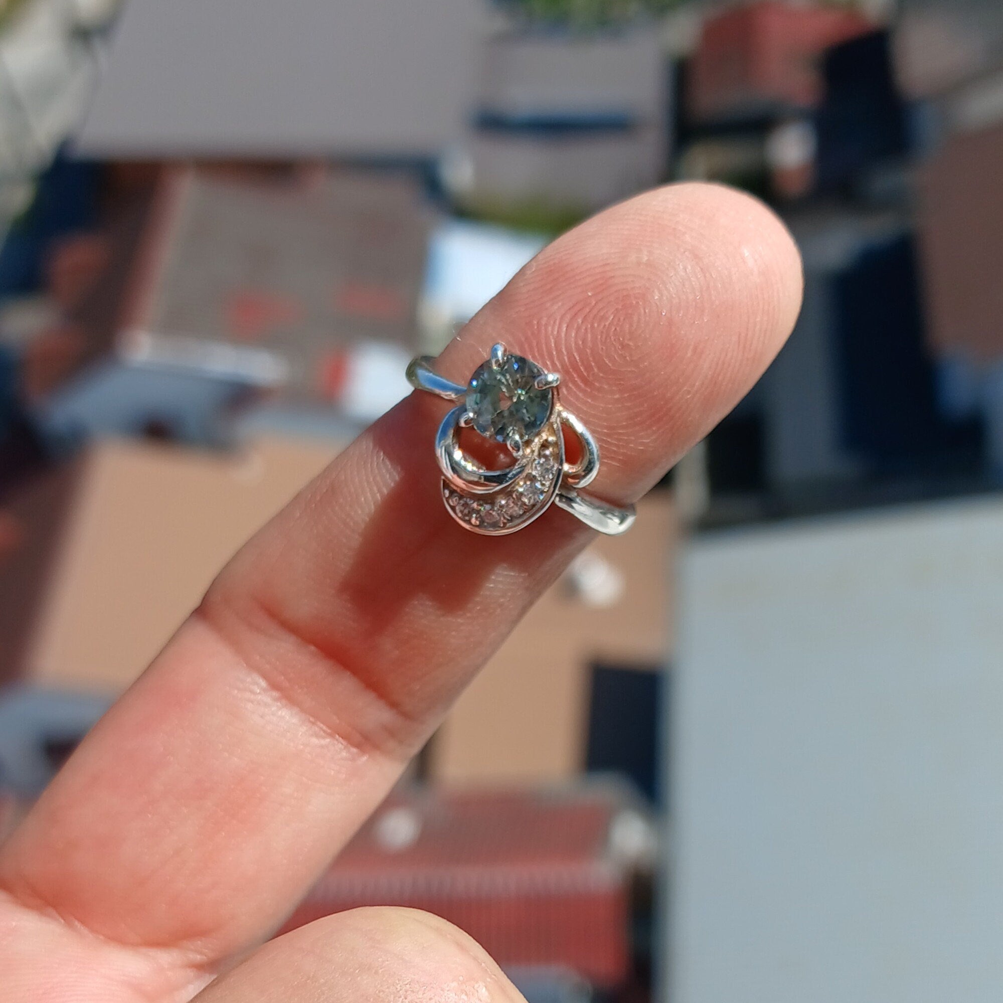 A stunning Blue Zircon Ring featuring a round cut blue gemstone surrounded by sparkling white CZ stones, set in polished sterling silver.