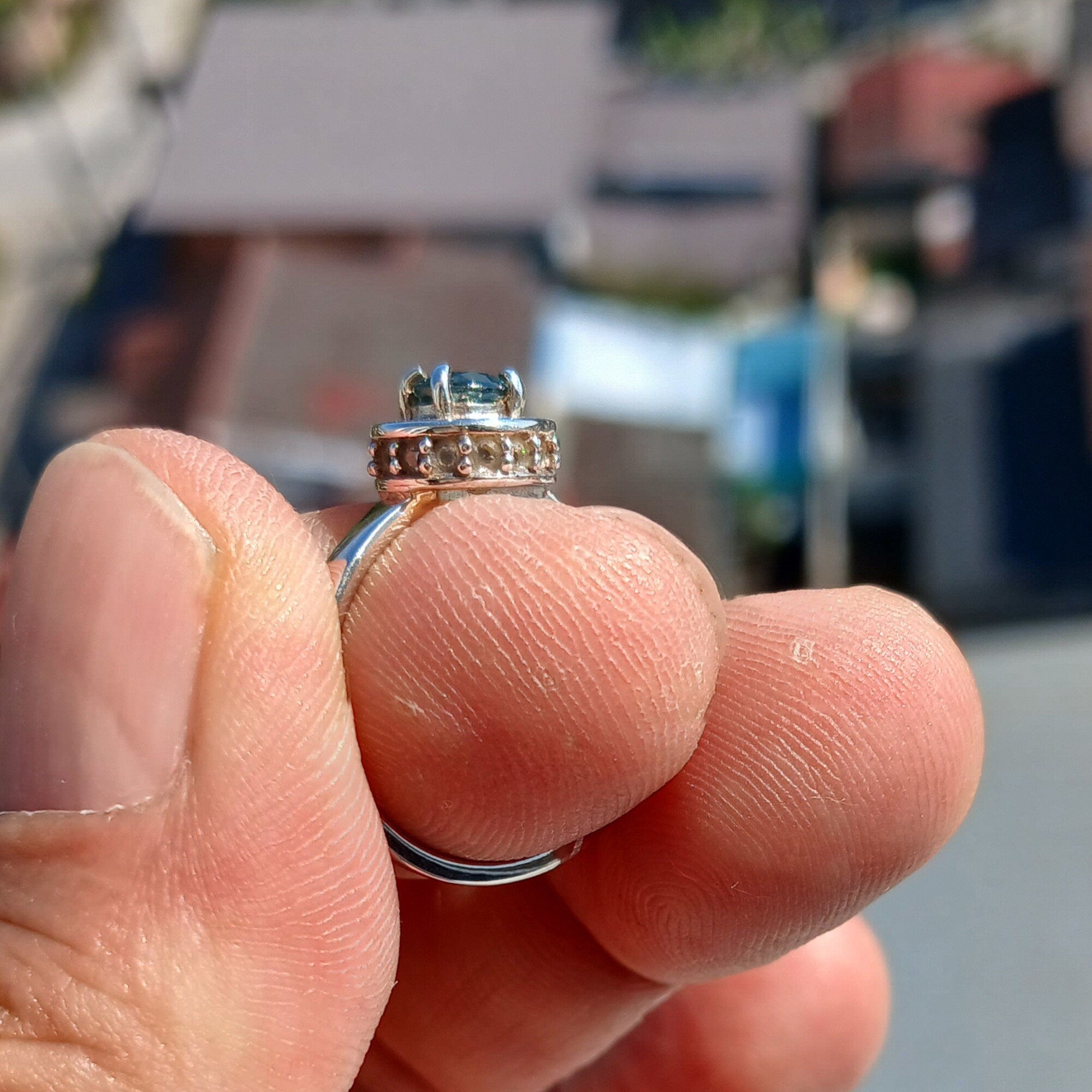 A stunning Blue Zircon Ring featuring a round cut blue gemstone at the center, surrounded by 14 sparkling white CZ stones, set in a polished sterling silver band.