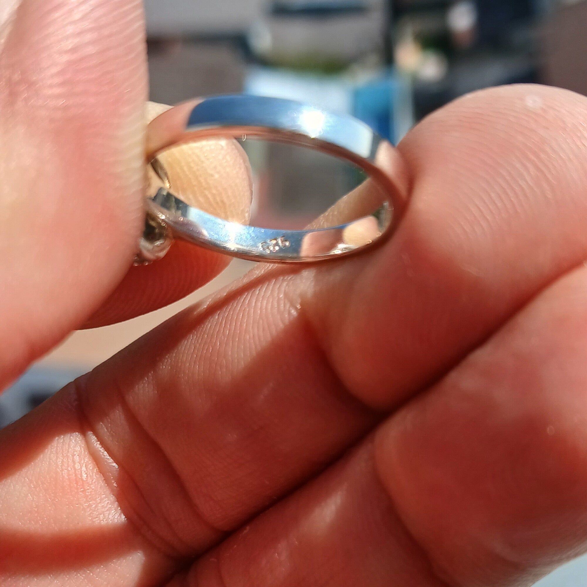 A stunning Blue Zircon Ring featuring a round cut blue gemstone at the center, surrounded by 14 sparkling white CZ stones, set in a polished sterling silver band.