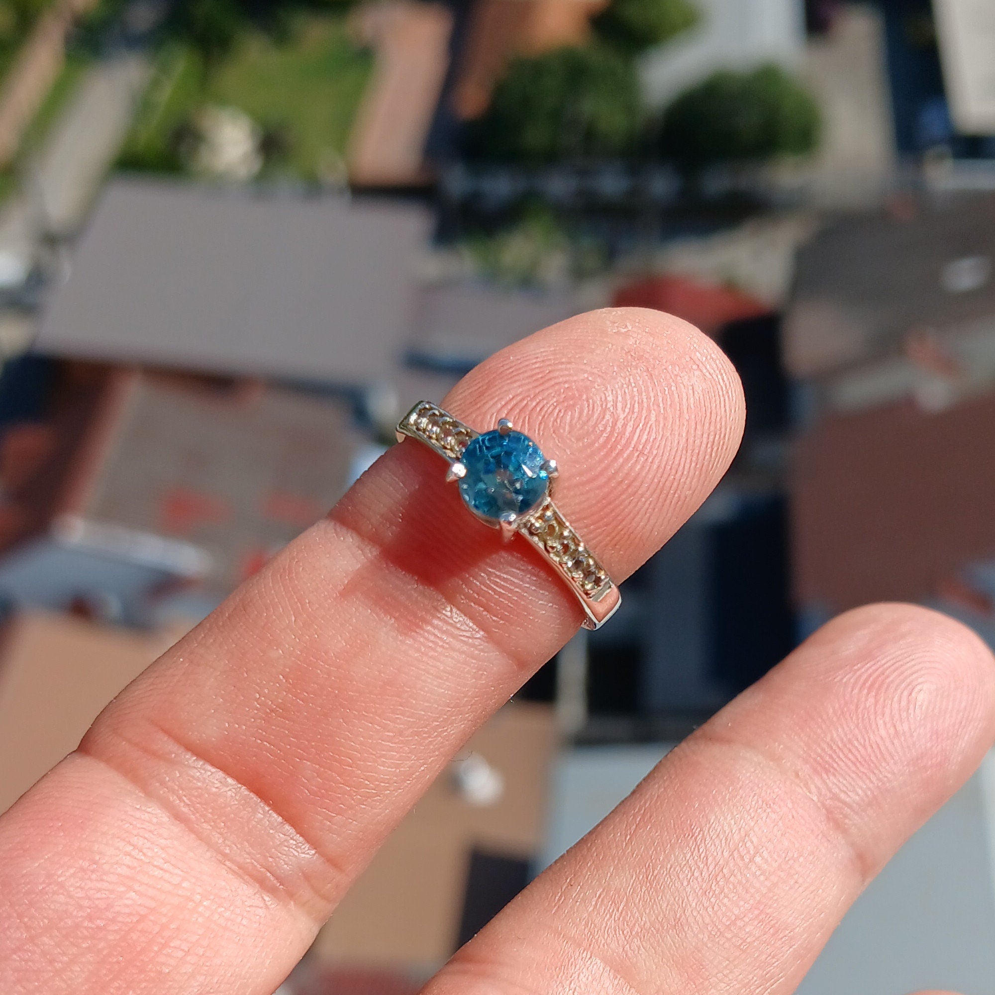A stunning blue zircon ring set in polished sterling silver, showcasing a round cut gemstone with a hallmarked 925 band.