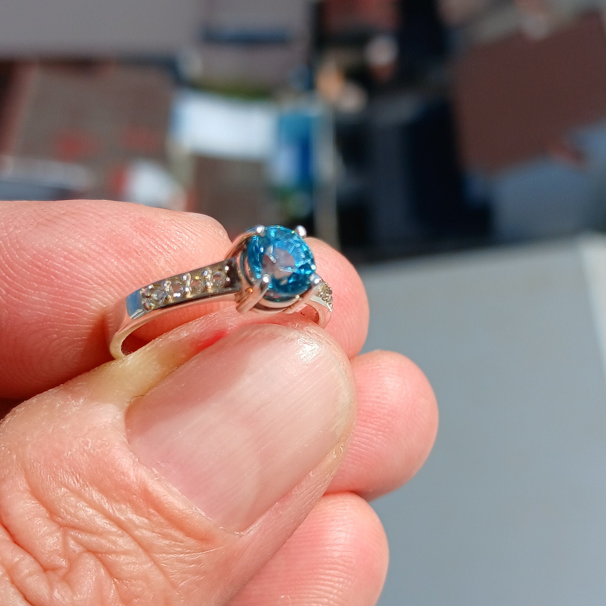 A stunning blue zircon ring set in polished sterling silver, showcasing a round cut gemstone with a hallmarked 925 band.
