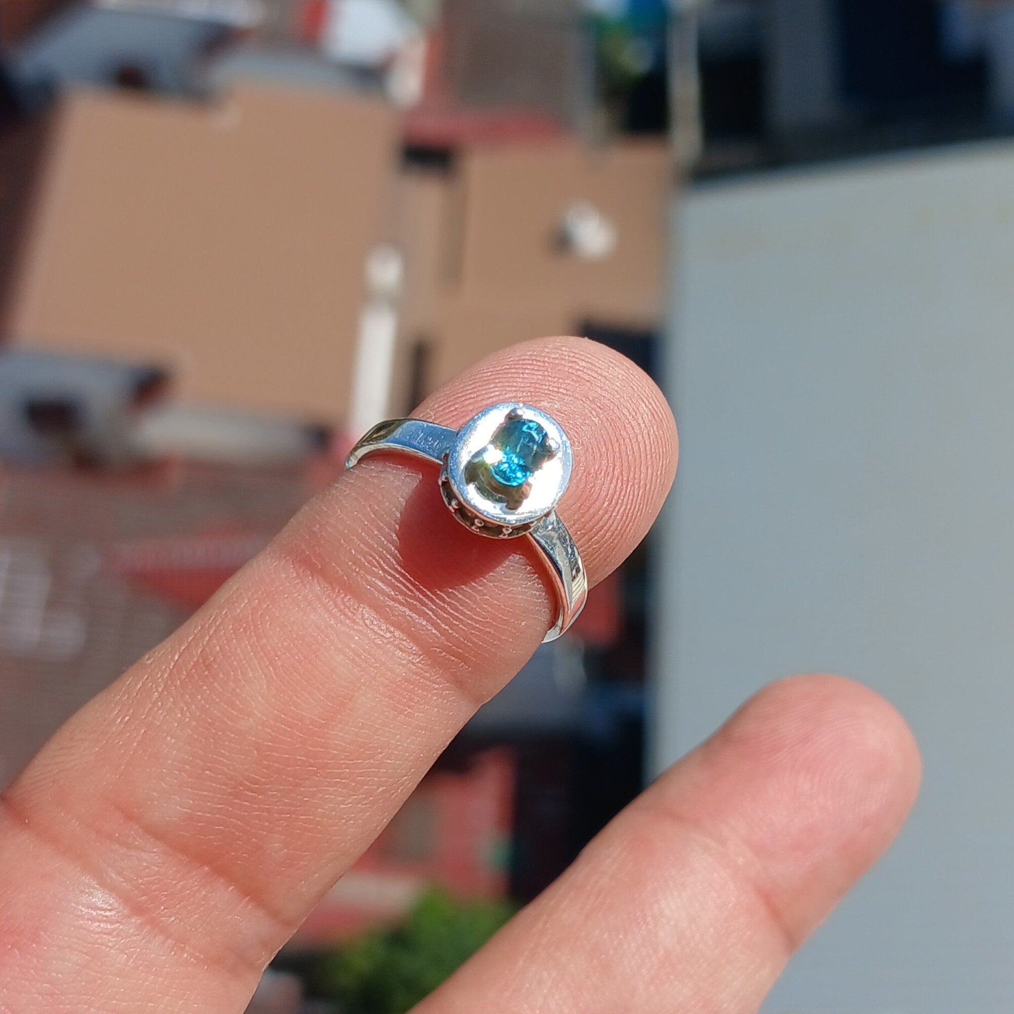 A stunning Blue Zircon Ring featuring a natural gemstone set in polished sterling silver, adorned with 14 white CZ stones.