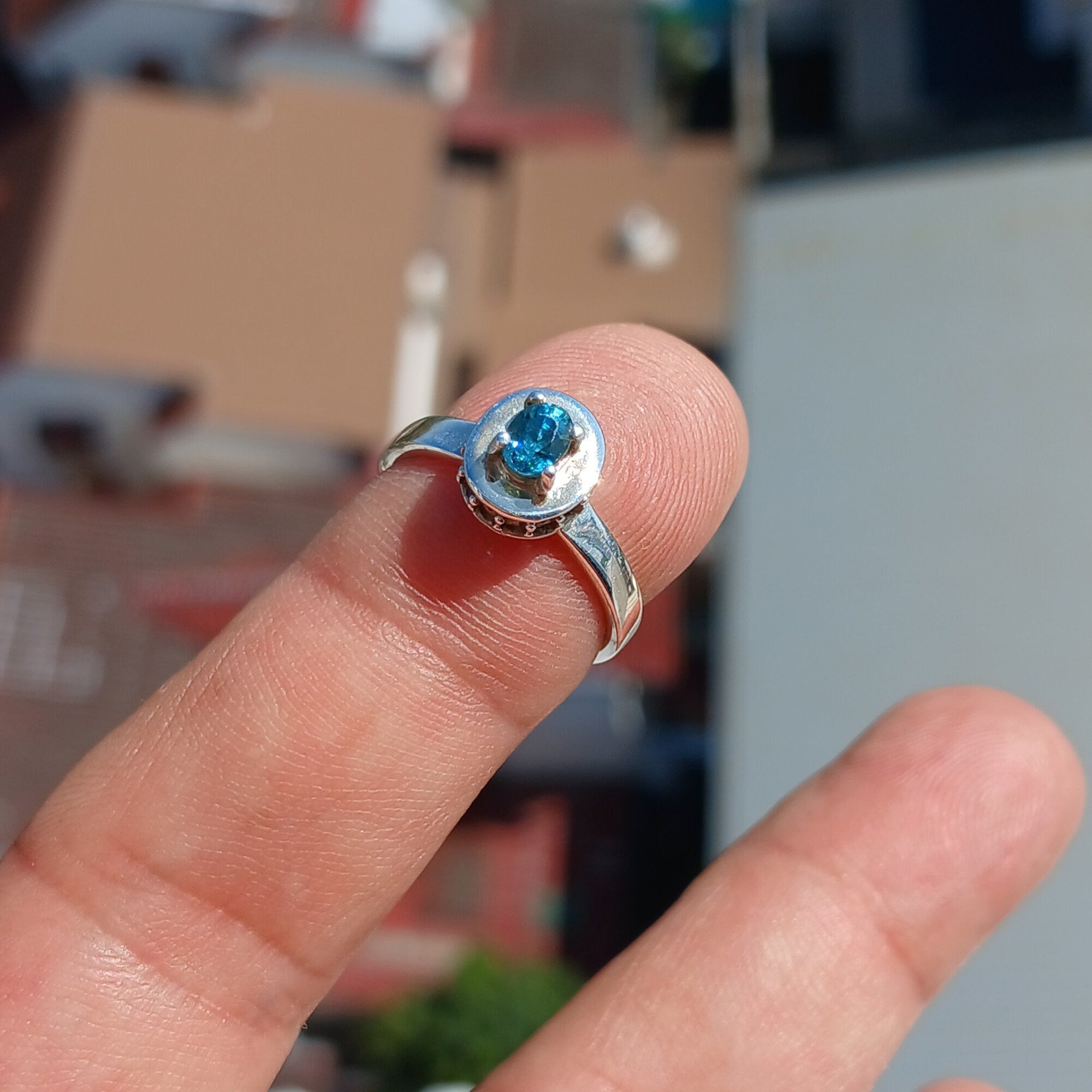 A stunning Blue Zircon Ring featuring a natural gemstone set in polished sterling silver, adorned with 14 white CZ stones.