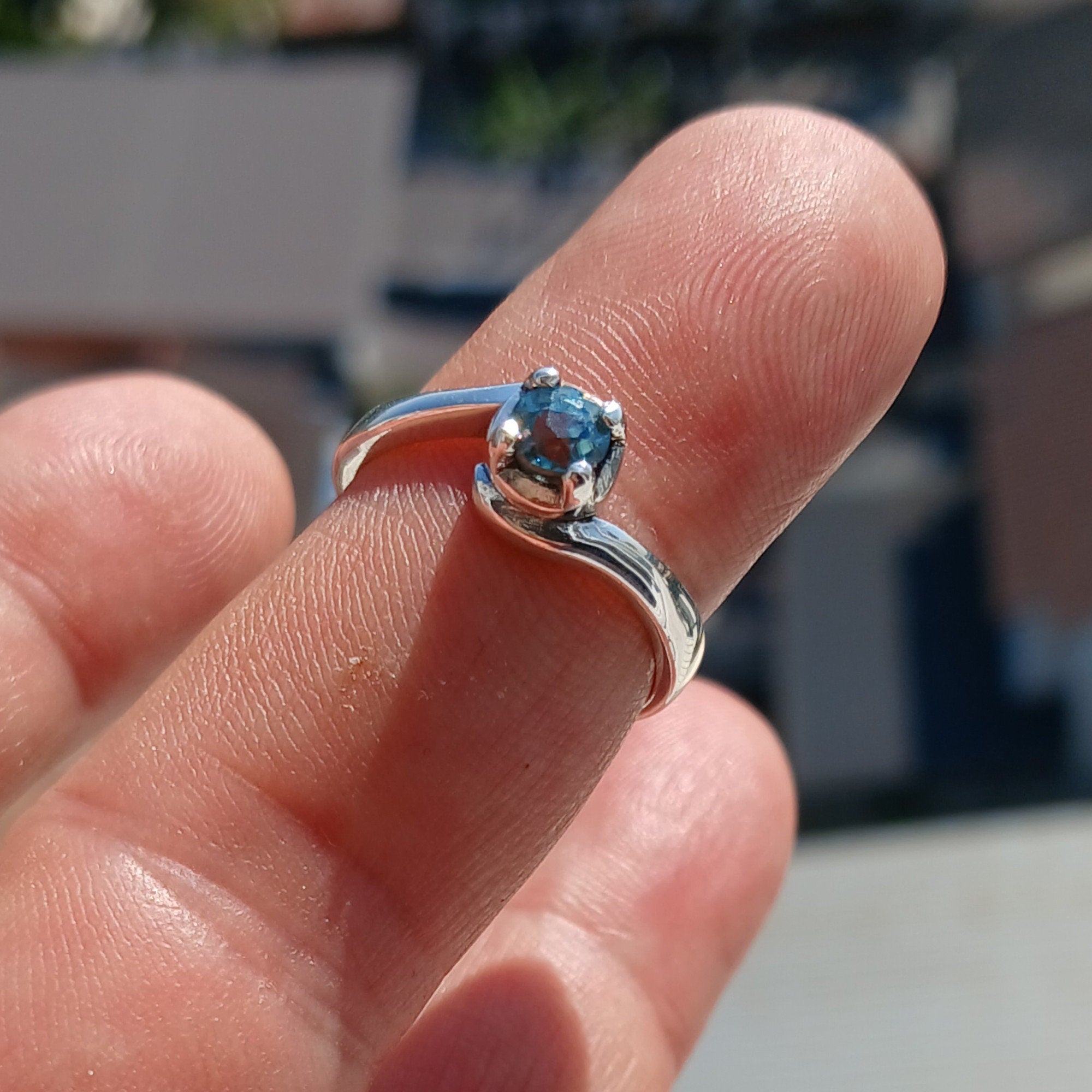 A stunning Blue Zircon Ring set in polished sterling silver, featuring a round cut blue gemstone in a solitaire design.