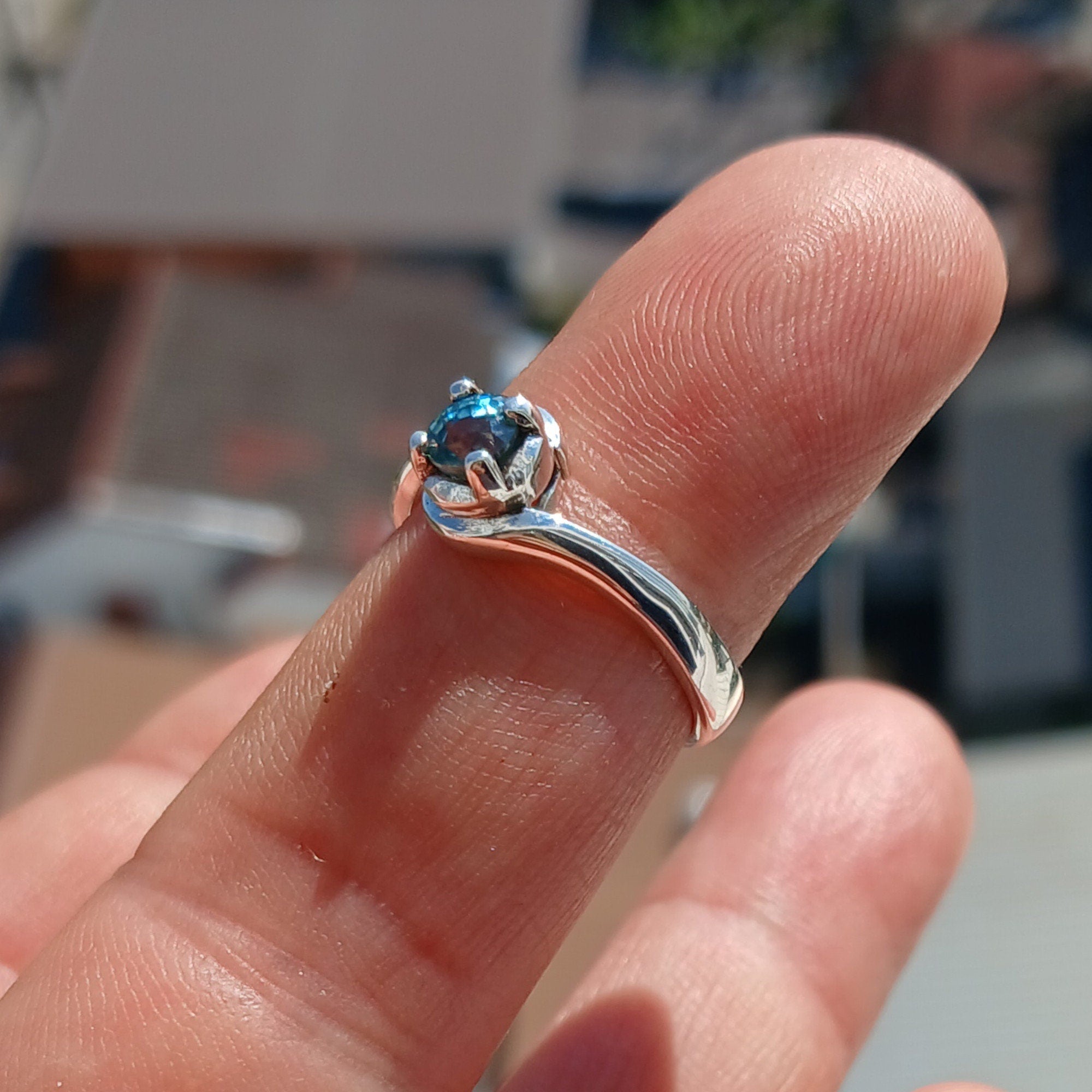 A stunning Blue Zircon Ring set in polished sterling silver, featuring a round cut blue gemstone in a solitaire design.