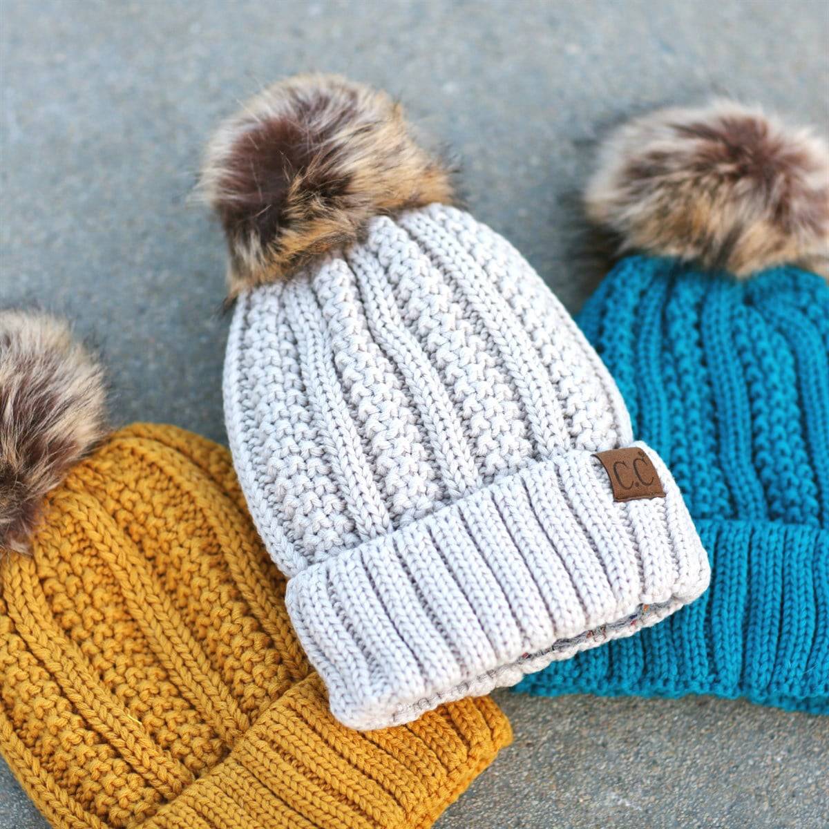 CC Bold Pom Accented Beanie with faux fur pom, cozy fleece lining, and authentic C.C.® branding, suitable for kids and adults.