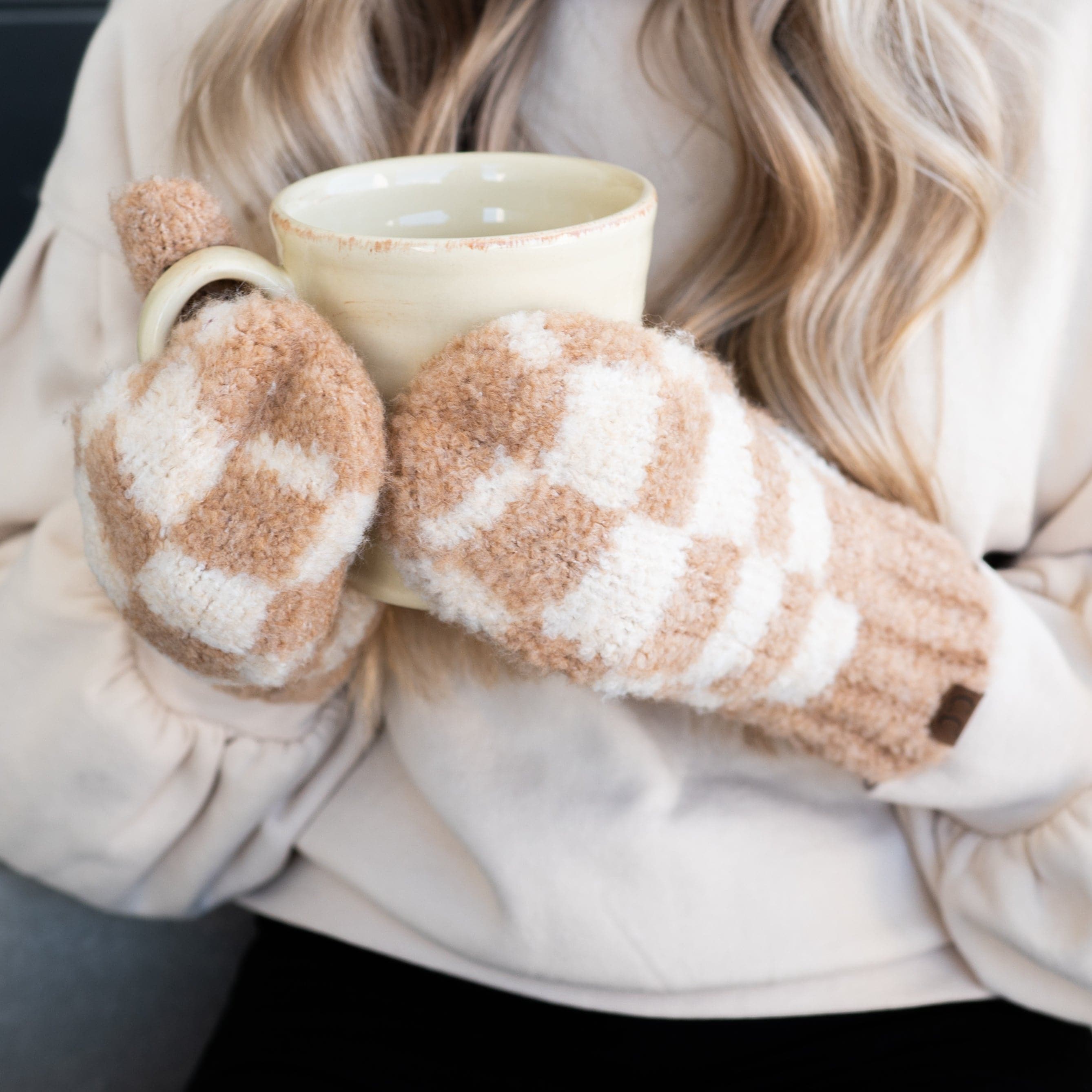 Hands in mittens holding mug