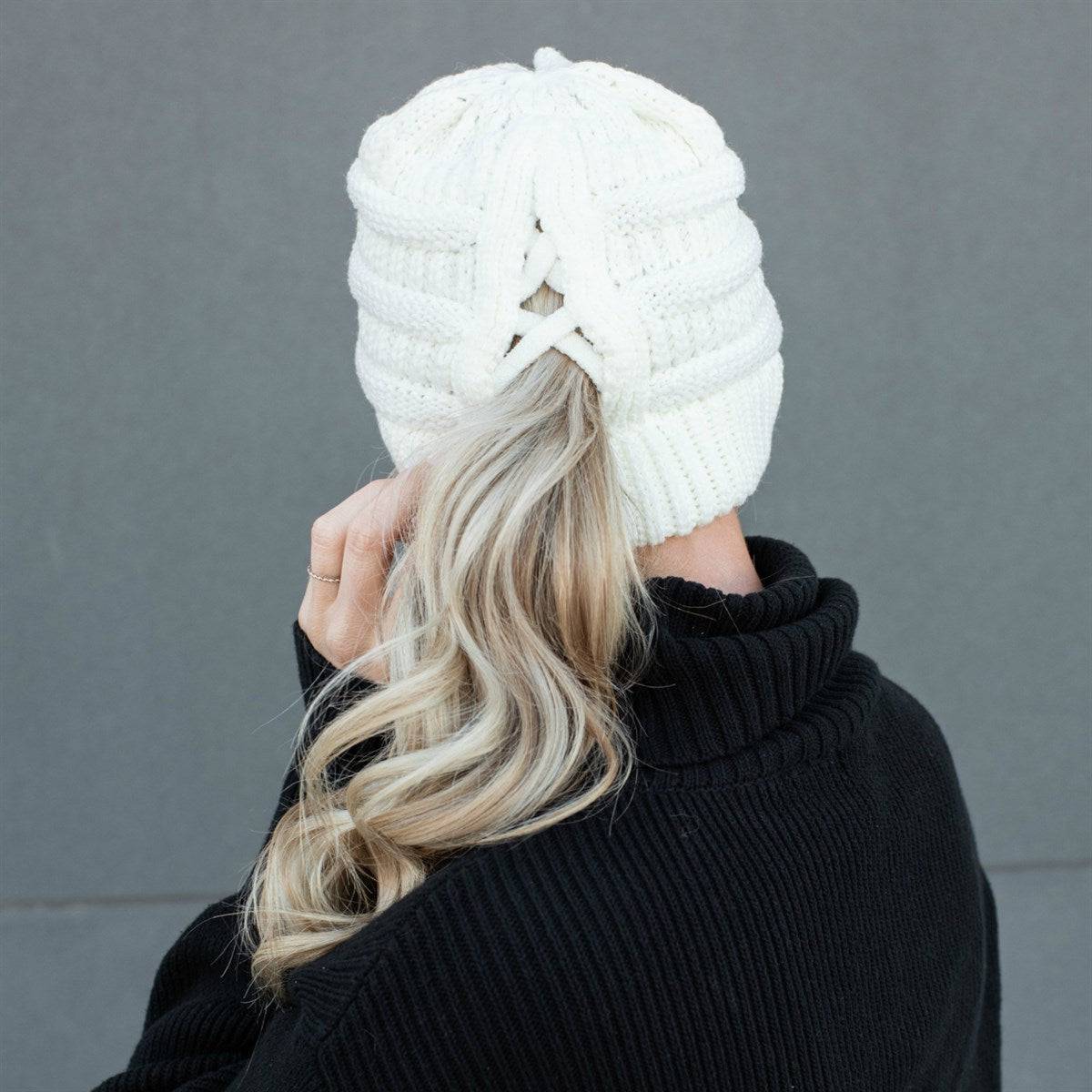 CC Criss-Cross Pony Beanie in cable-knit design, featuring a criss-cross back for ponytails and messy buns, made from super soft acrylic.