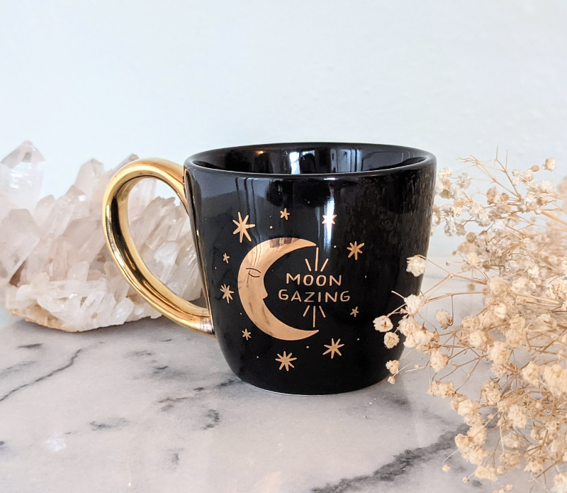 Celestial Tea Set featuring a mystical tea towel, a ceramic mug with gold designs, and a brass sun spoon, perfect for herbal tea rituals.