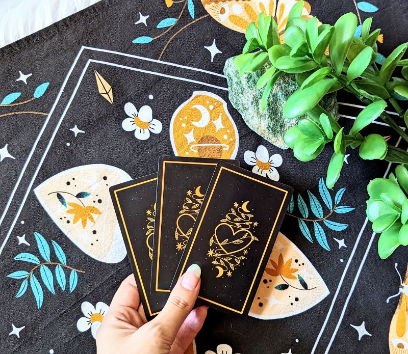 Celestial Tea Set featuring a mystical tea towel, a ceramic mug with gold designs, and a brass sun spoon, perfect for herbal tea rituals.