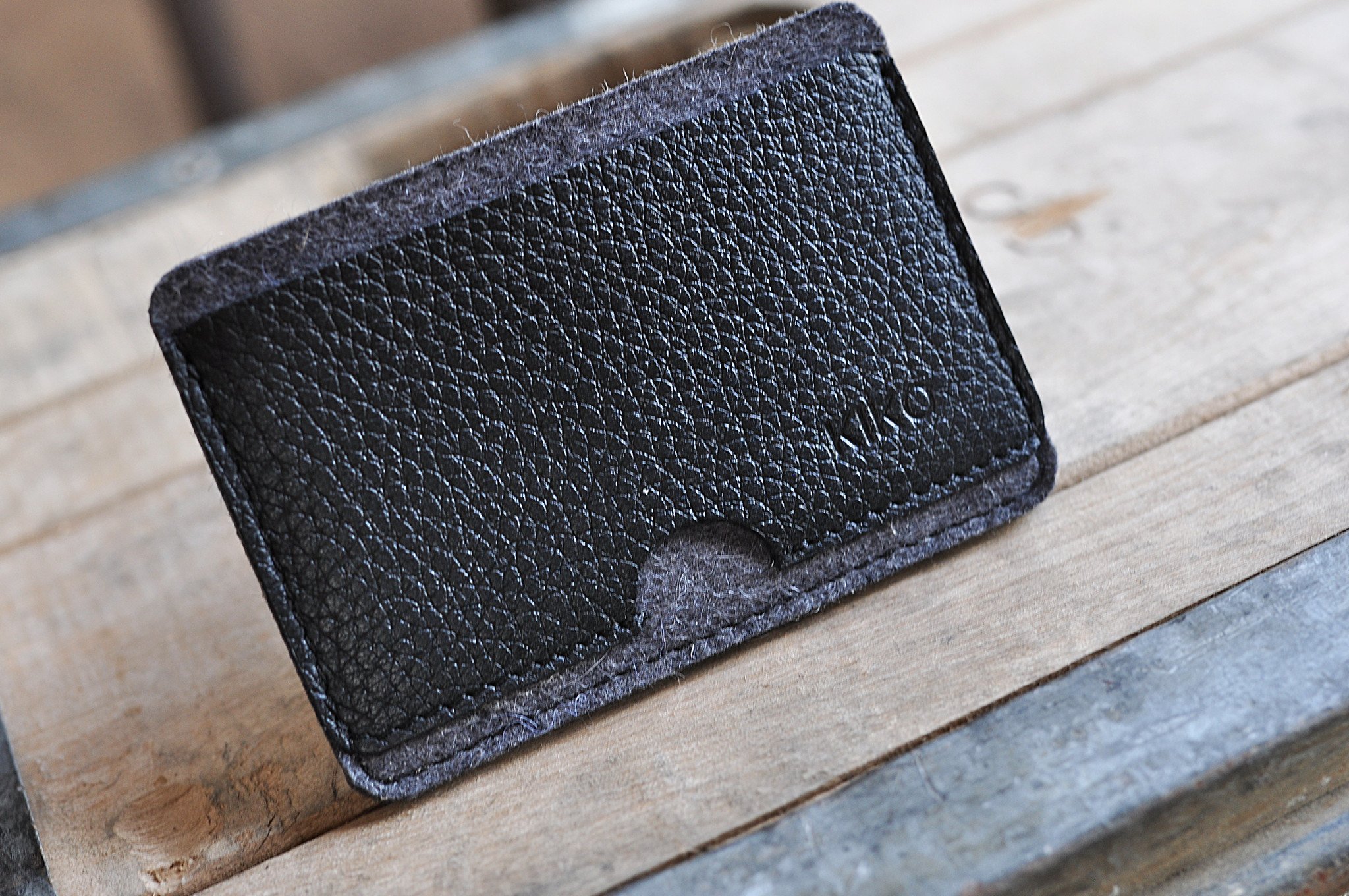 A stylish Combo Card Case made from wool felt and vegetable tanned cowhide leather, featuring rustic heat burnished details and two slots for cards and cash.