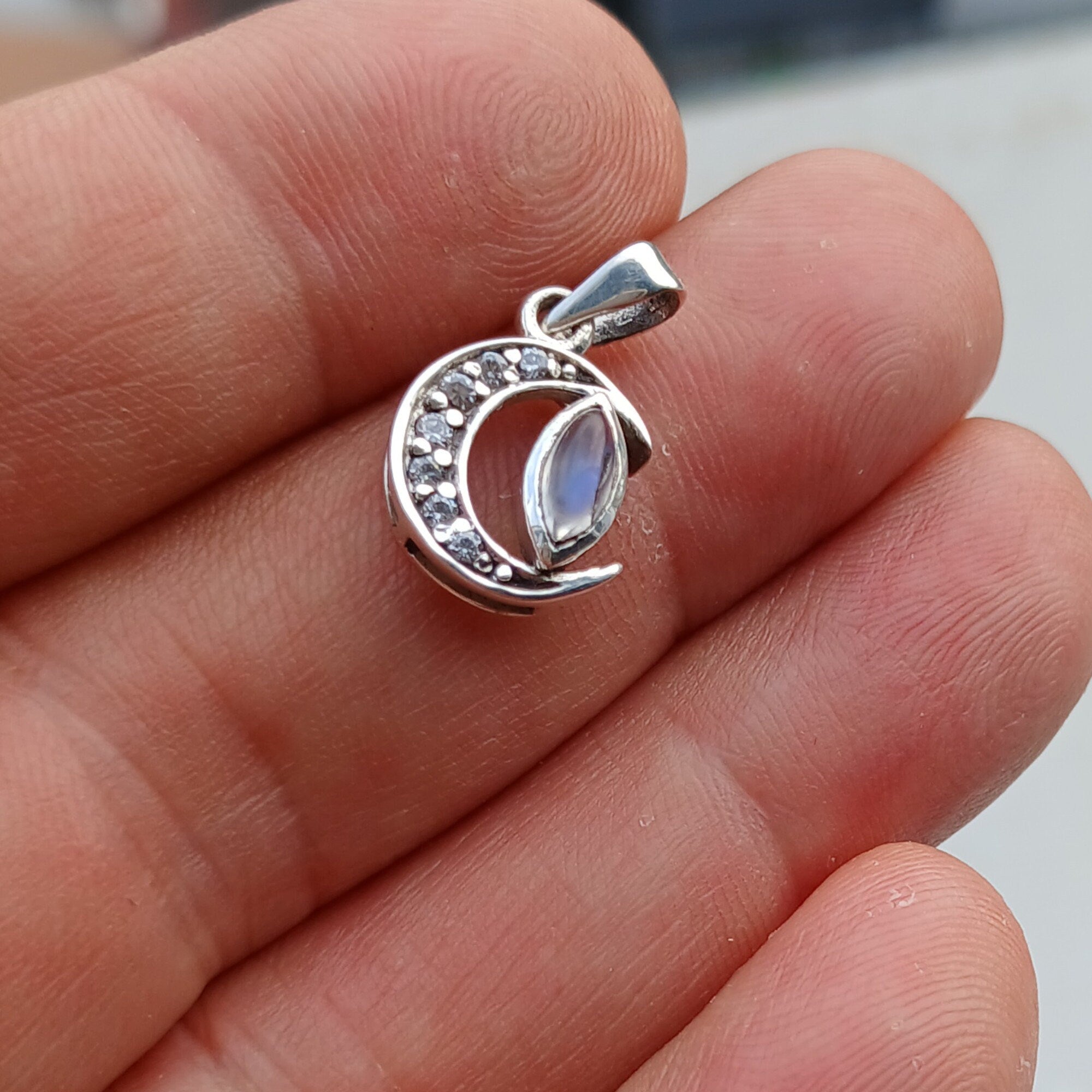 Crescent Moonstone Pendant in sterling silver with cubic zirconias, showcasing a unique crescent moon design and a visible crack in the moonstone.