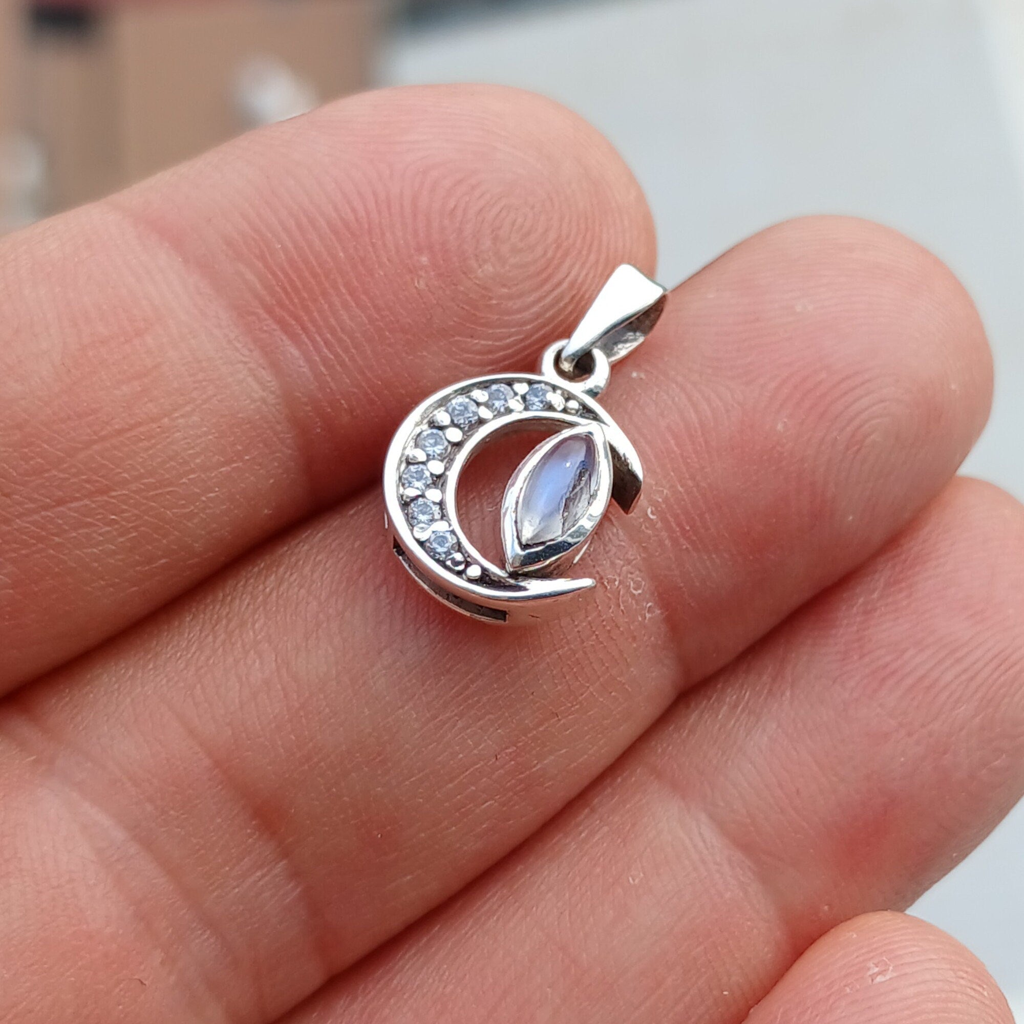 Crescent Moonstone Pendant in sterling silver with cubic zirconias, showcasing a unique crescent moon design and a visible crack in the moonstone.