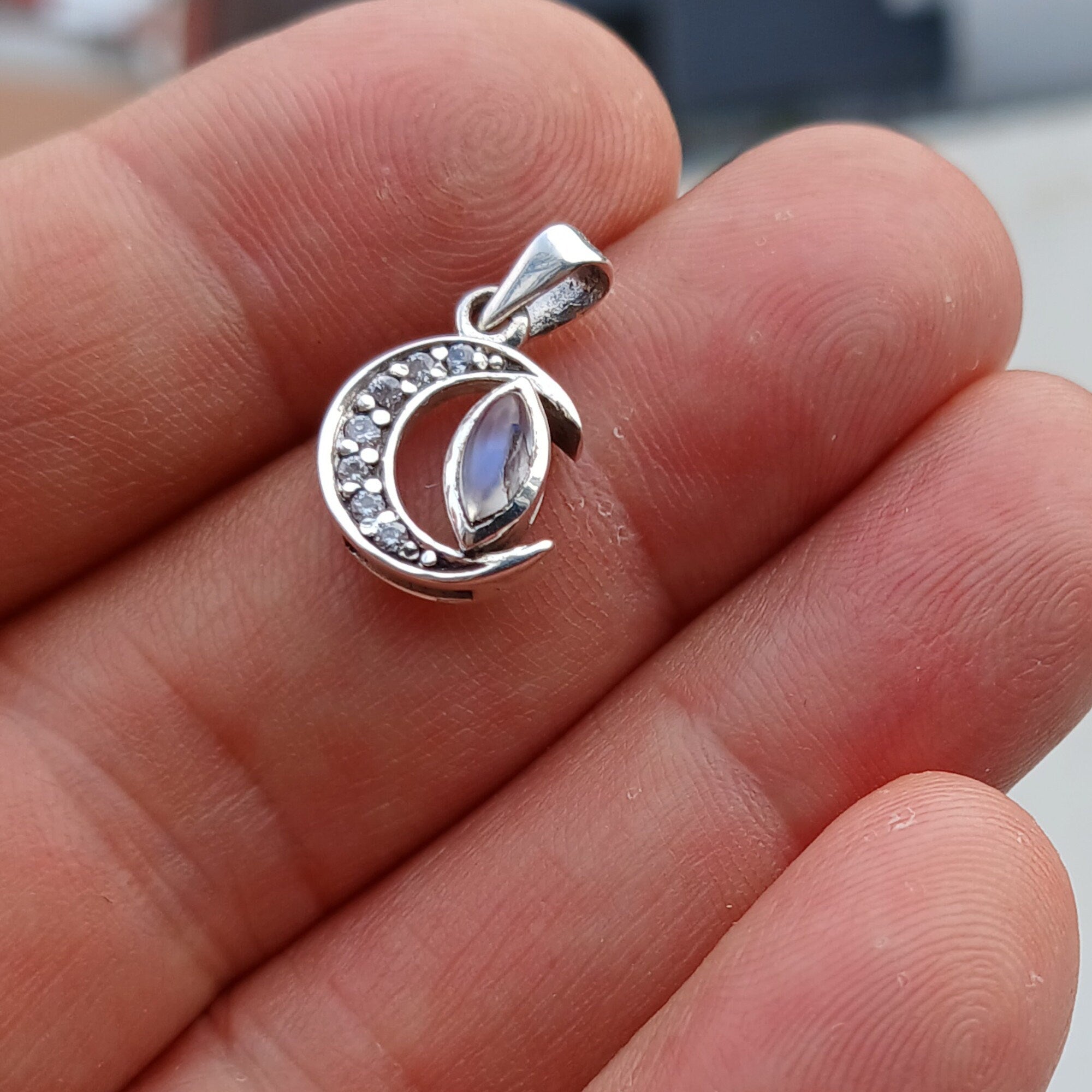 Crescent Moonstone Pendant in sterling silver with cubic zirconias, showcasing a unique crescent moon design and a visible crack in the moonstone.