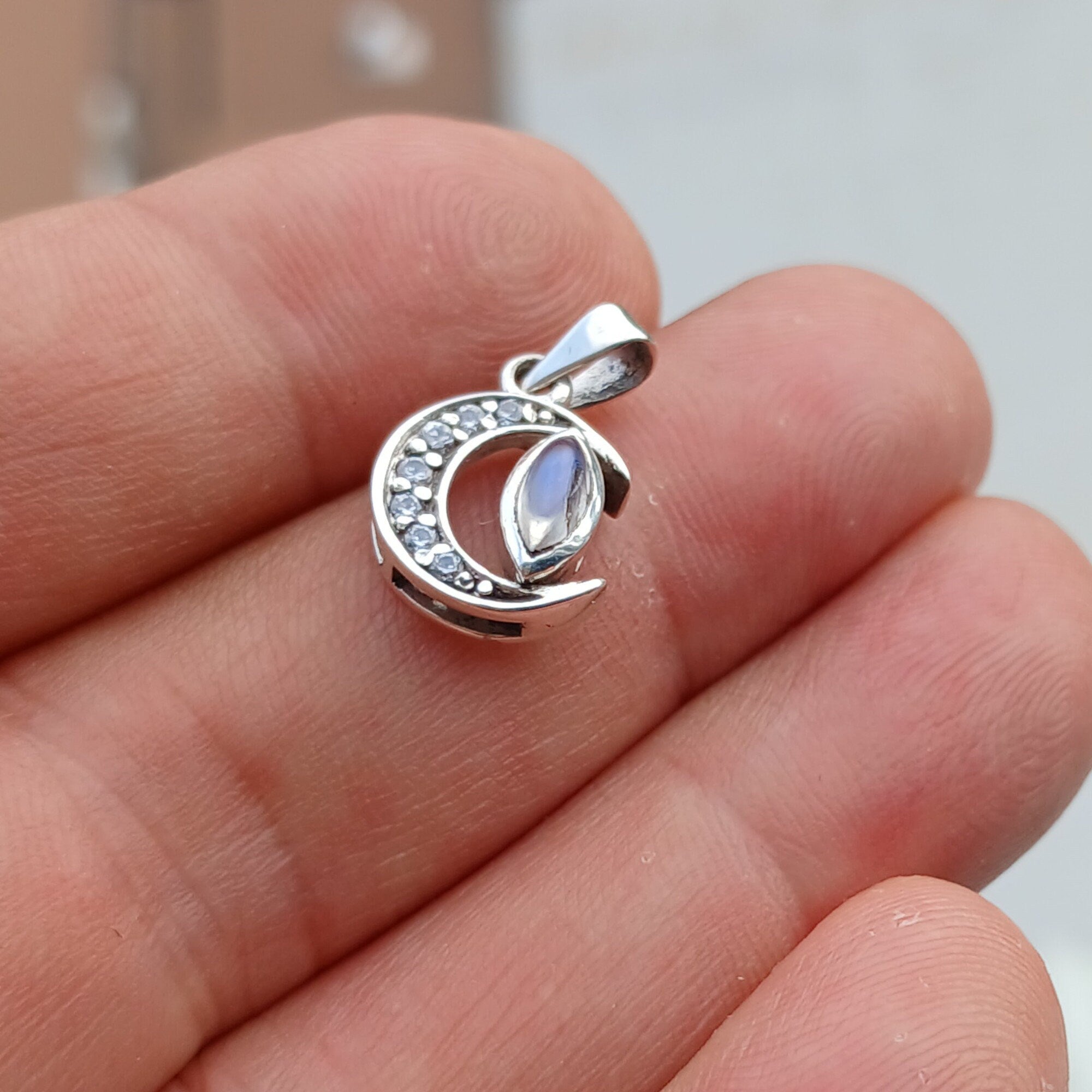 Crescent Moonstone Pendant in sterling silver with cubic zirconias, showcasing a unique crescent moon design and a visible crack in the moonstone.