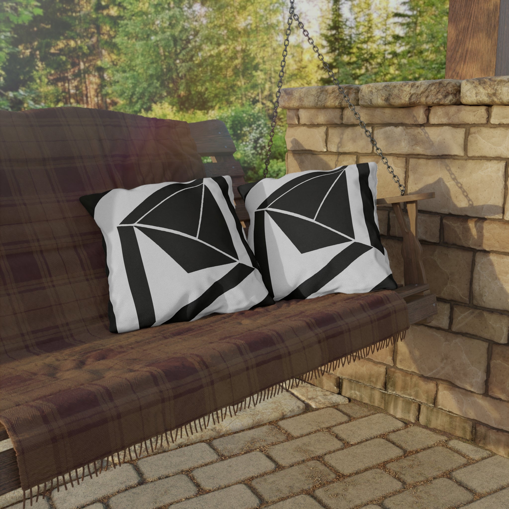 Decorative indoor/outdoor pillow featuring a black and white geometric pattern, ideal for enhancing outdoor spaces.
