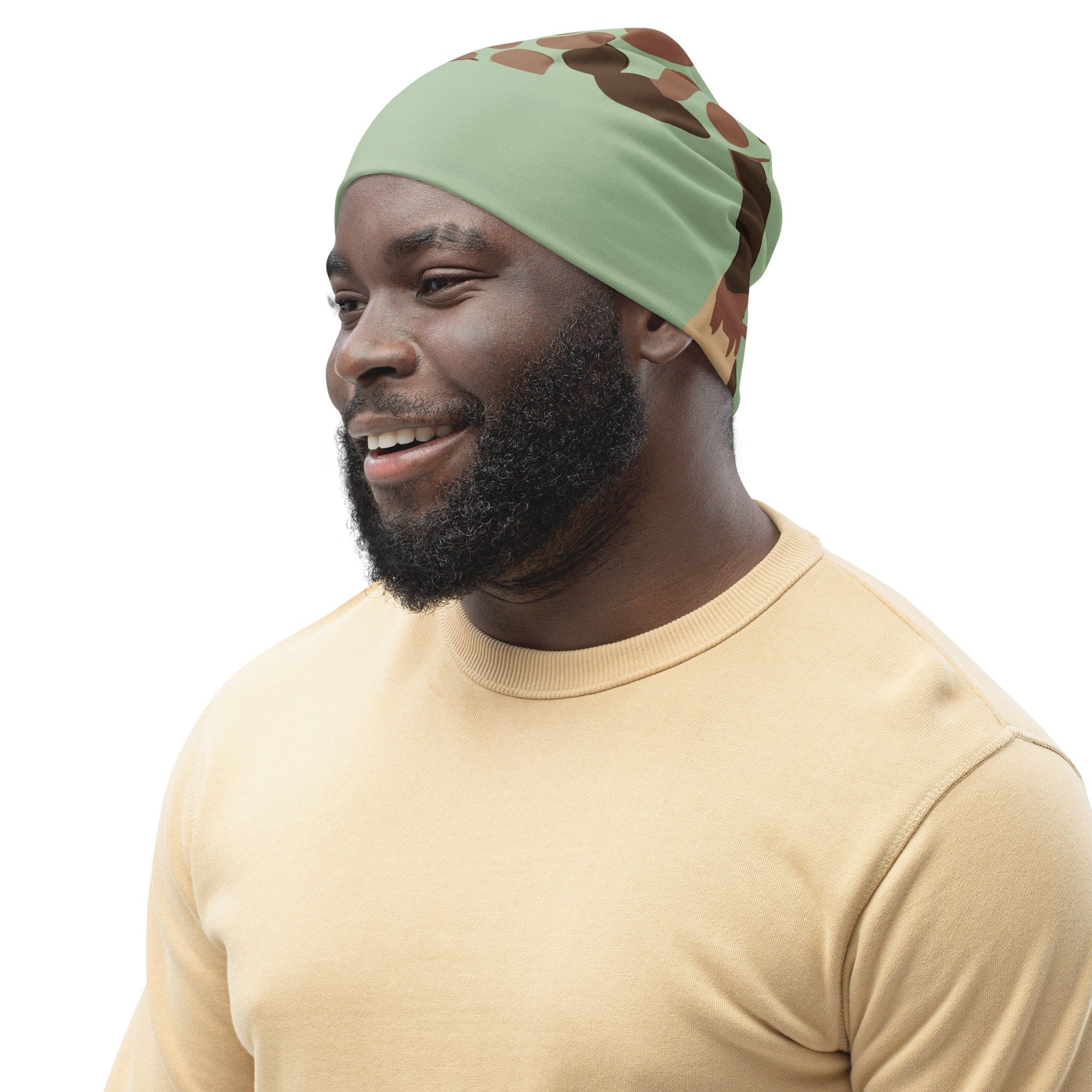 Double-layered beanie hat in green and beige spotted print, showcasing its soft fabric and stylish design.