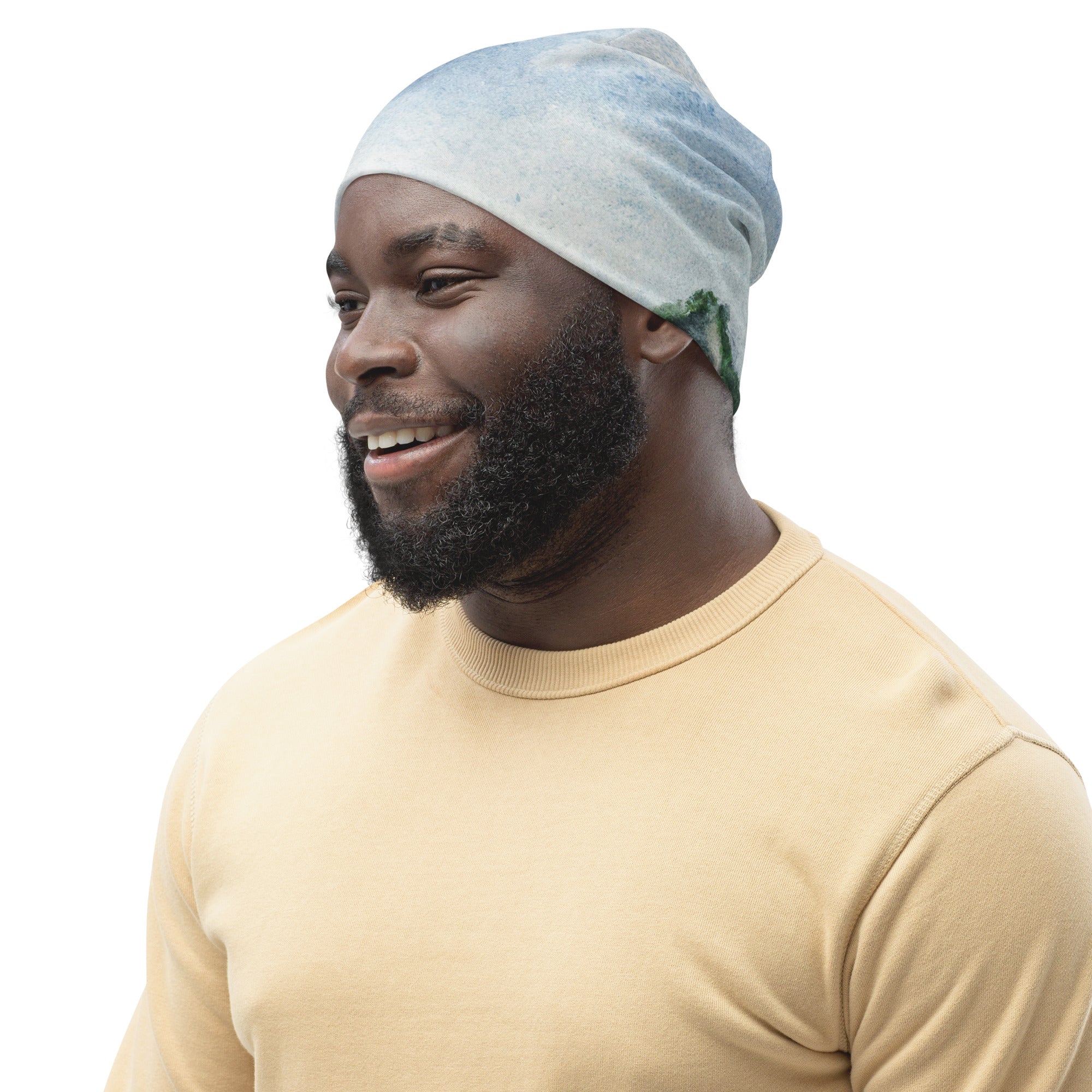 Double-layered beanie hat with green mountainside landscape and blue sky print, showcasing its stylish design and cozy fabric.