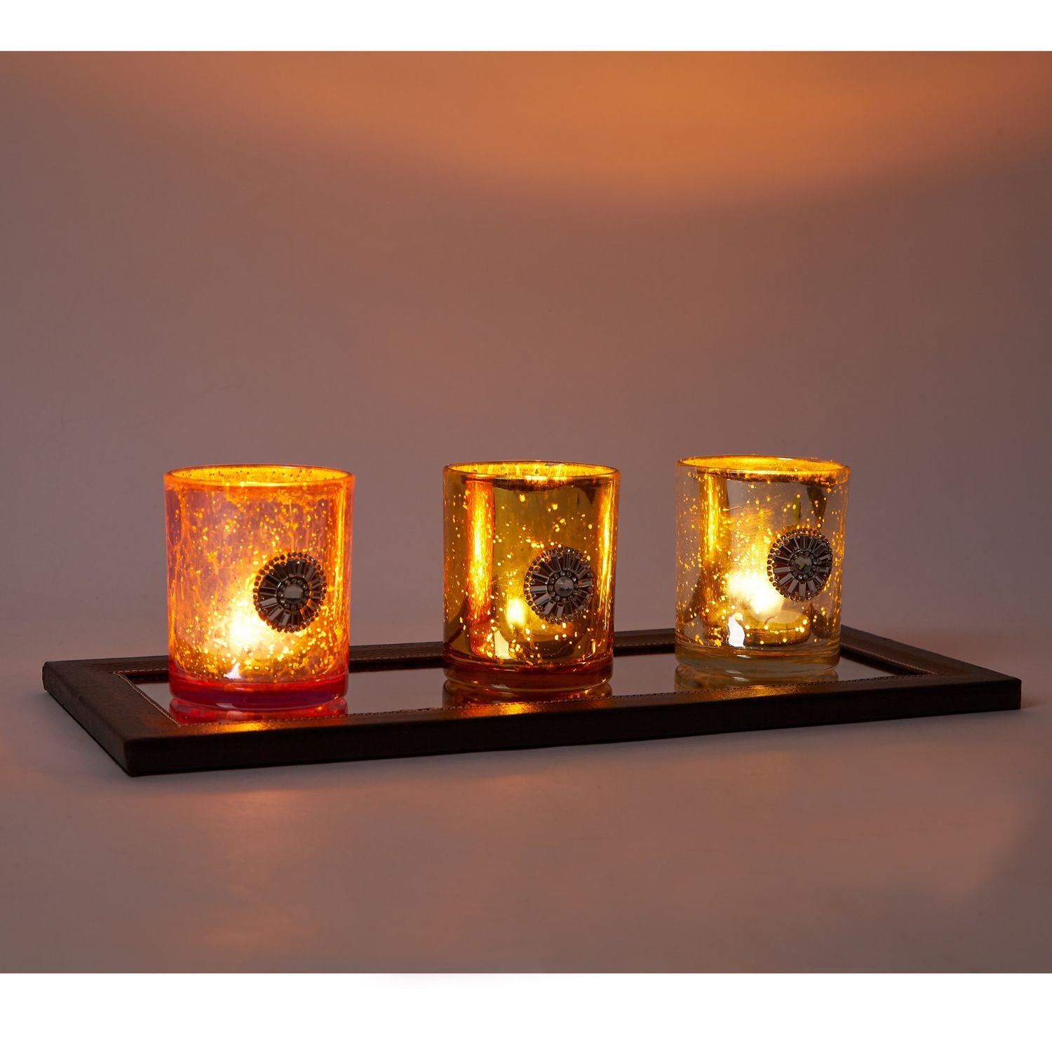 A set of three handmade Austrian crystal tumbler candle holders on a faux leather edged glass mirror tray, reflecting light beautifully.
