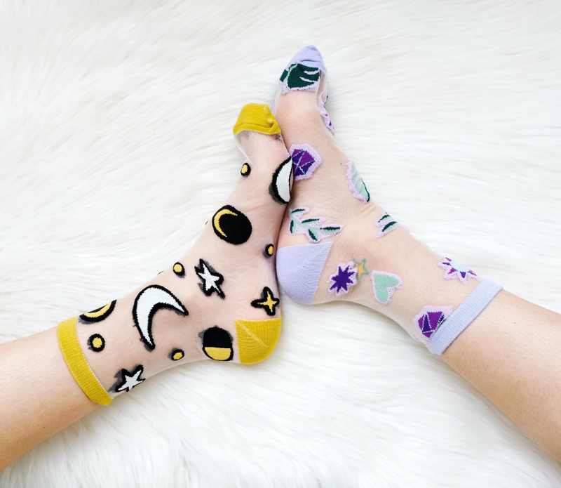A pair of stylish embroidered mesh ankle socks featuring celestial designs with moons, stars, and botanical motifs in lavender and sunshine yellow trims.