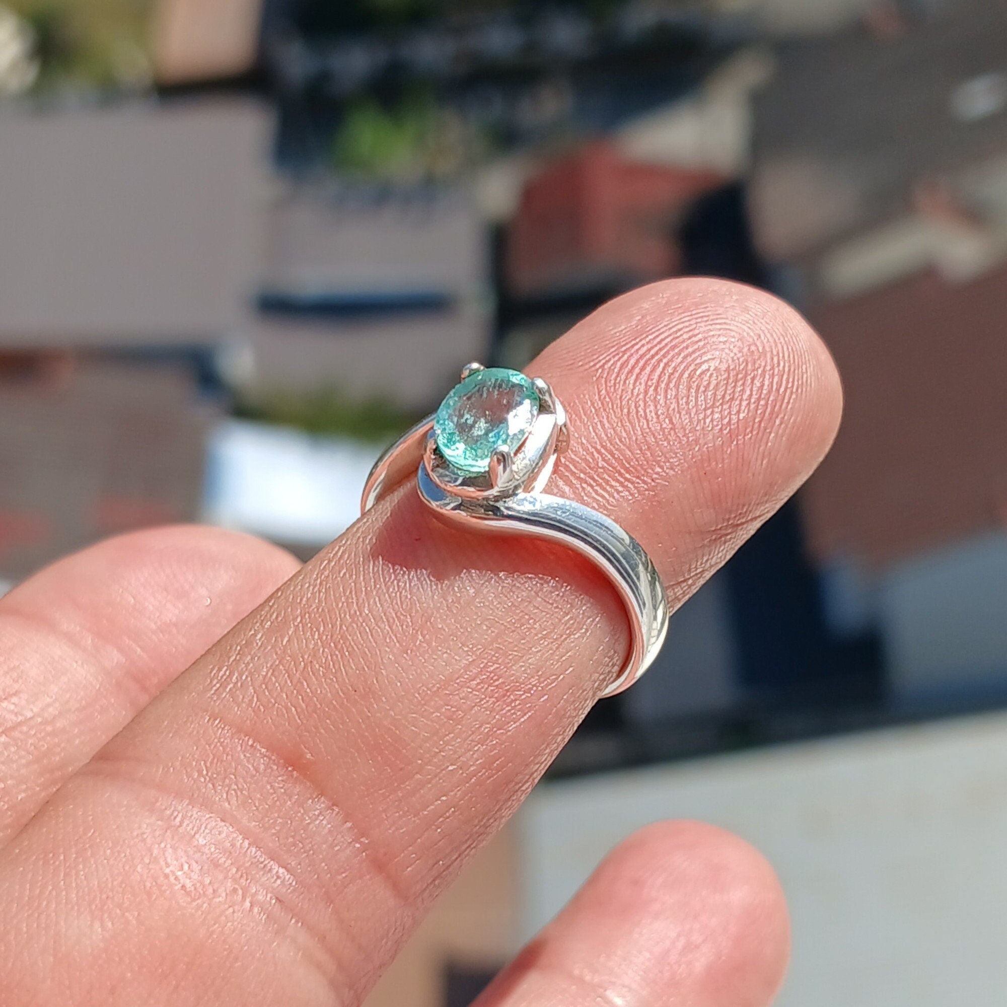 A beautiful emerald ring featuring a natural green emerald set in a polished sterling silver band, showcasing its oval shape and exquisite clarity.