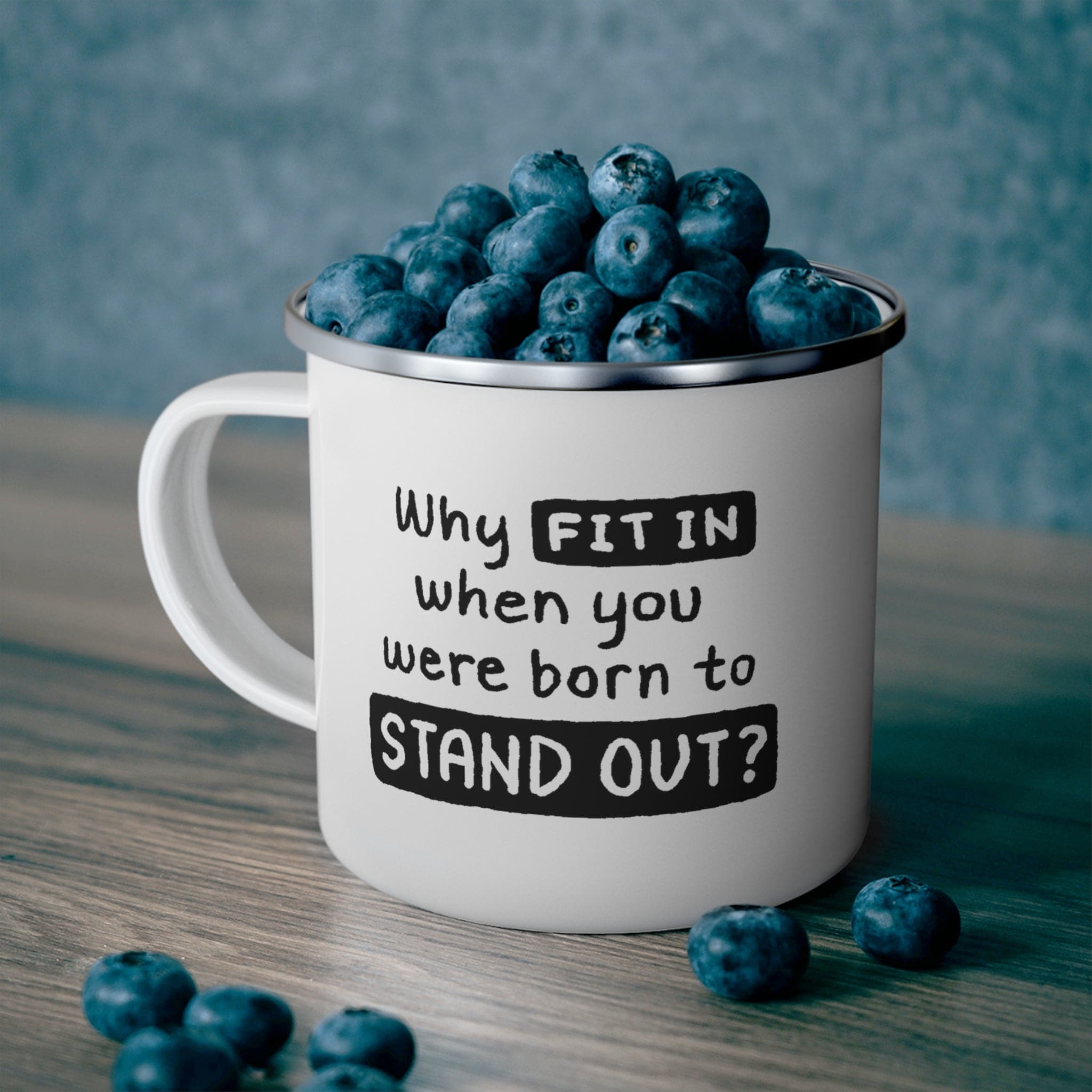 A stylish black enamel camping mug with rounded corners and a C-handle, featuring the phrase 'Why Fit In When You Were Born to Stand Out'.